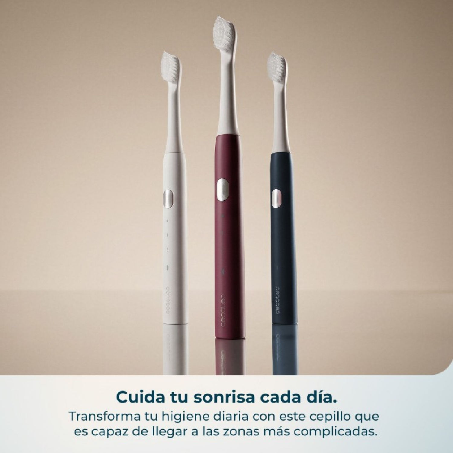 Tres cepillos de dientes eléctricos en blanco, burdeos y azul oscuro sobre una superficie reflectante con fondo beige.