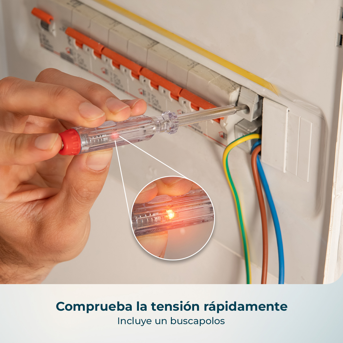 Una mano usa un buscapolos con luz roja encendida en un cuadro eléctrico.