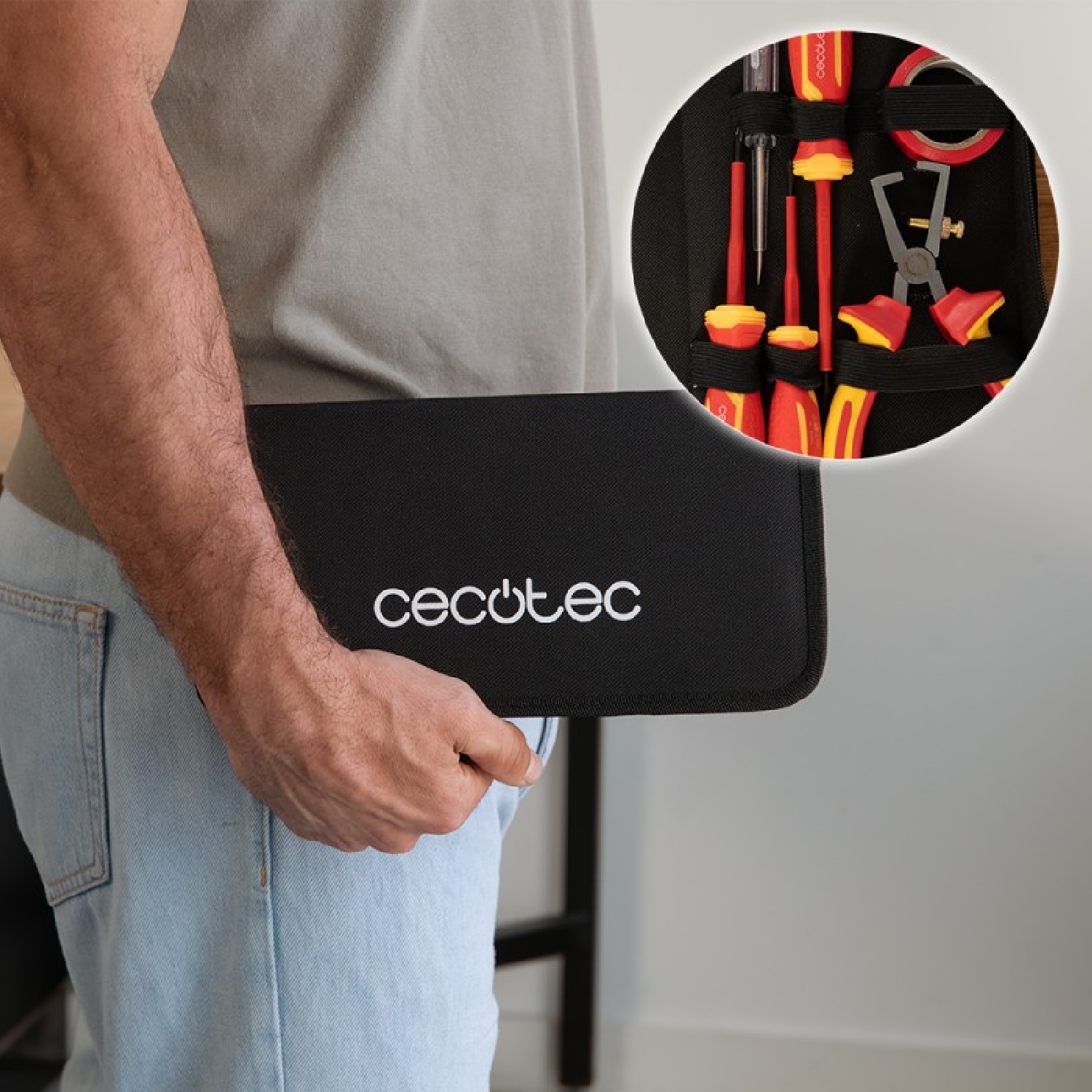 Persona che tiene in mano una borsa porta attrezzi nera Cecotec con utensili rossi nel riquadro.