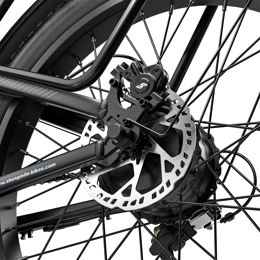 Primer plano de la rueda trasera, freno de disco y radios de una bicicleta negra sobre fondo oscuro.