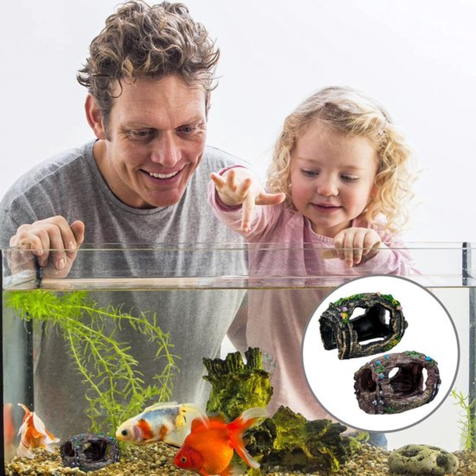 Ein Vater und seine Tochter lächeln und beobachten drei bunte Fische in einem Aquarium.