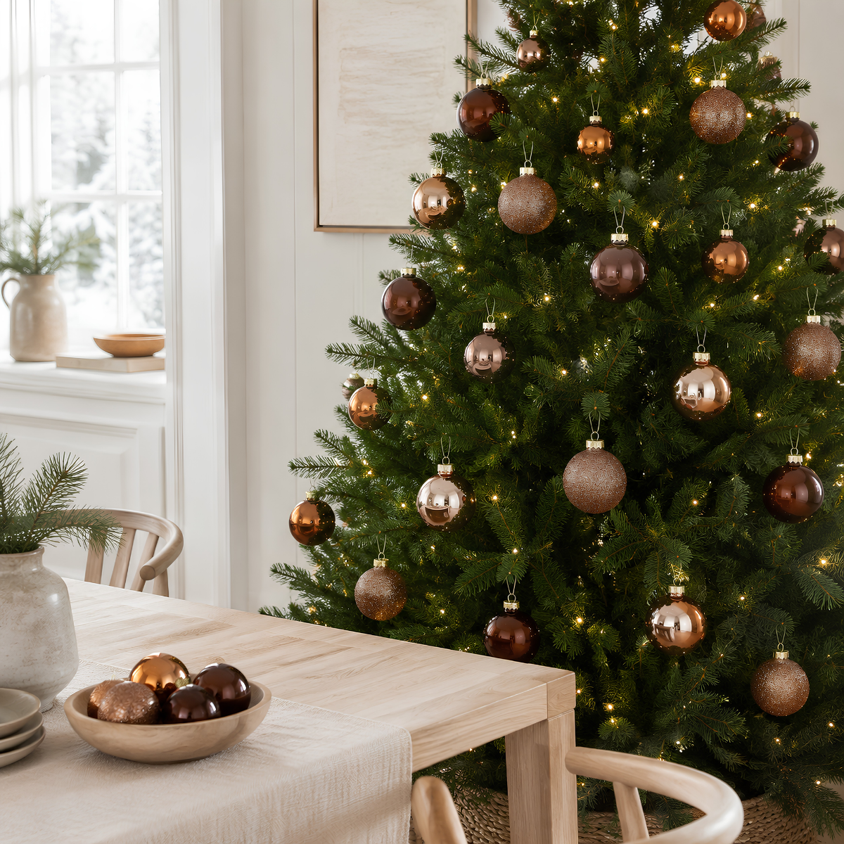 A decorated Christmas tree with brown ornaments and lights stands next to a wooden table.