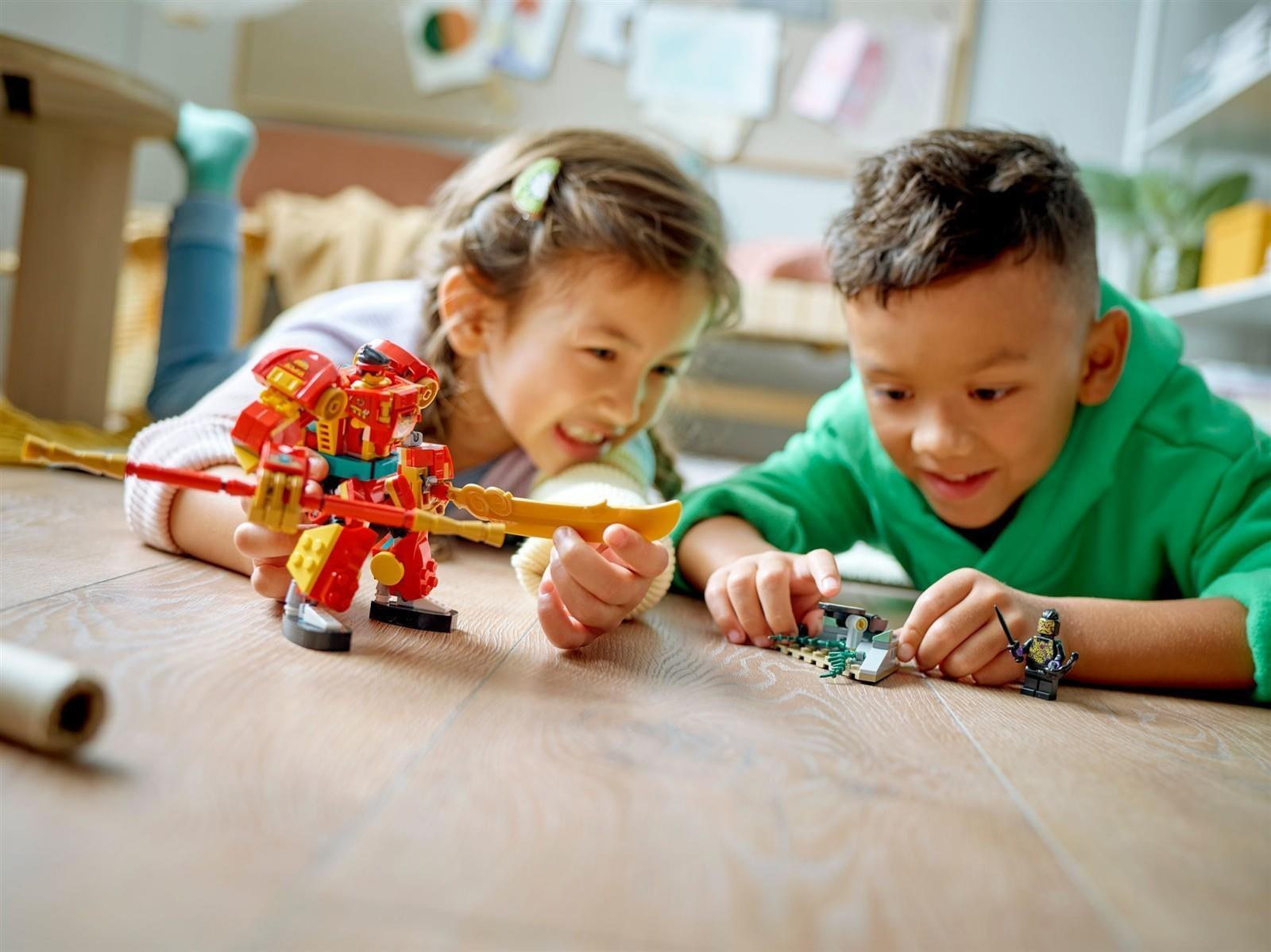 Zwei Kinder liegen auf dem Holzfußboden und spielen im Wohnzimmer mit LEGO-Spielzeug.