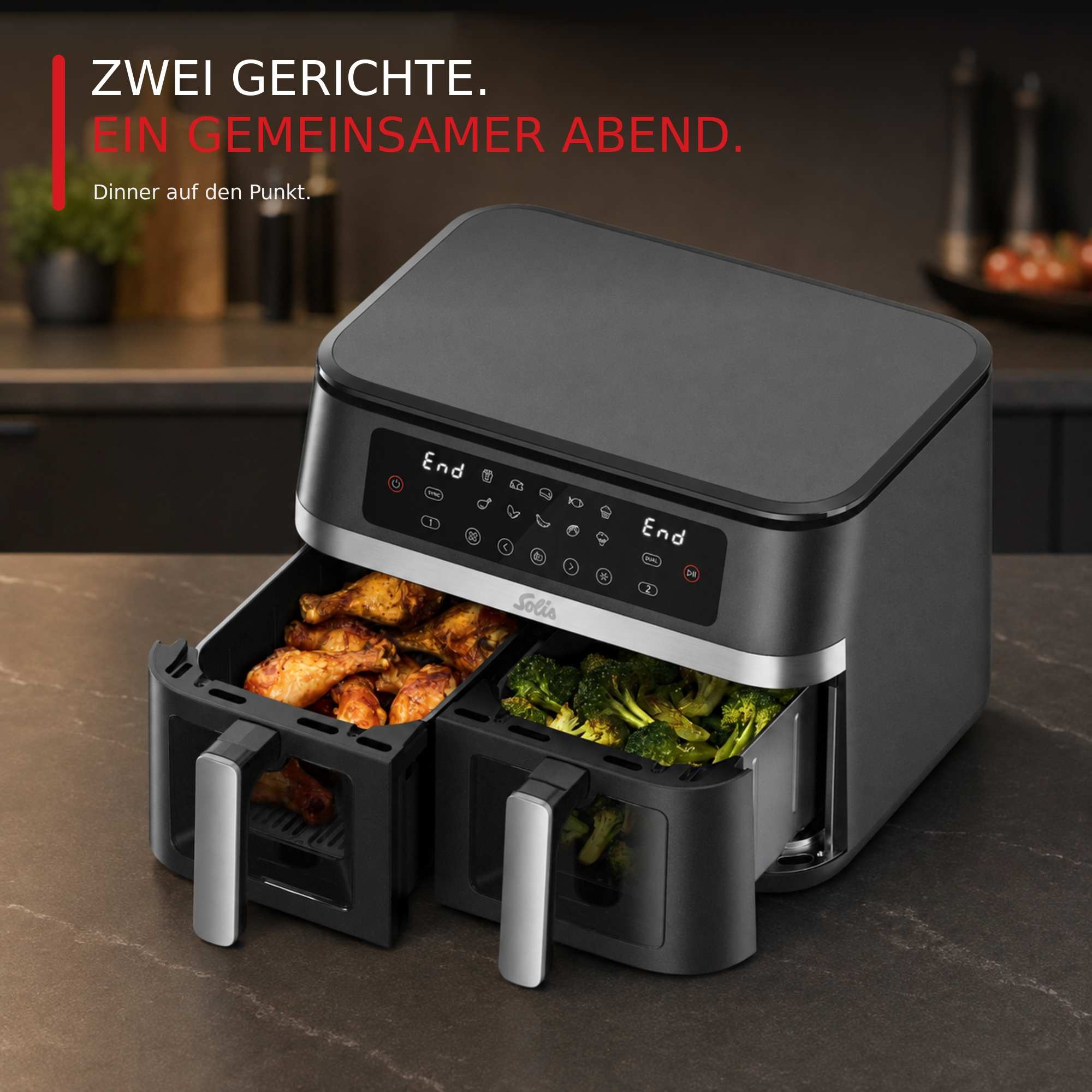Eine graue Solis Heißluftfritteuse mit zwei offenen Körben voller Hähnchenschenkel und Brokkoli.