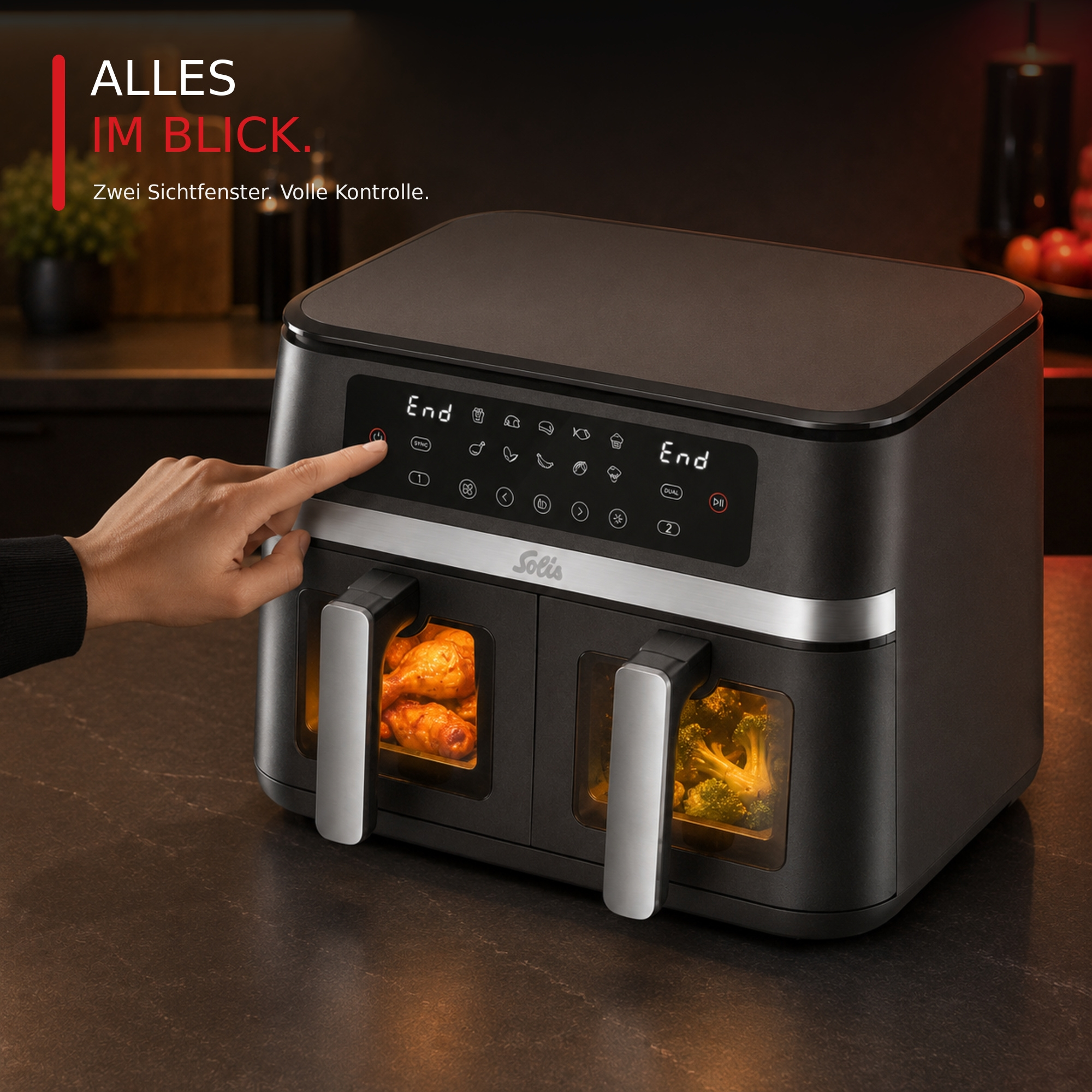 Hand bedient eine schwarze Solis-Heißluftfritteuse mit zwei beleuchteten Sichtfenstern für Hähnchen und Broccoli.