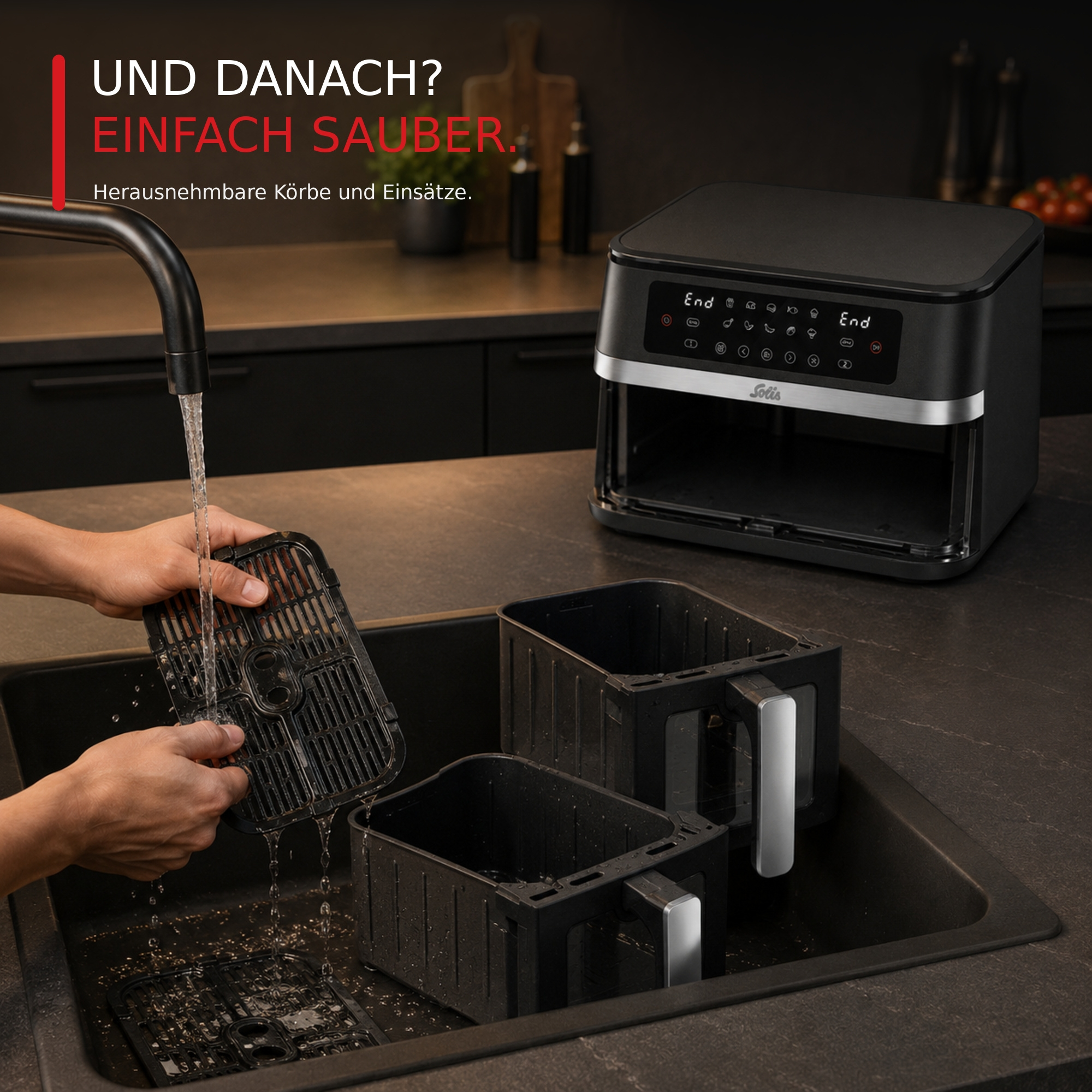 Person wäscht die herausnehmbaren Körbe und Einsätze einer schwarzen Heißluftfritteuse im Küchenwaschbecken.