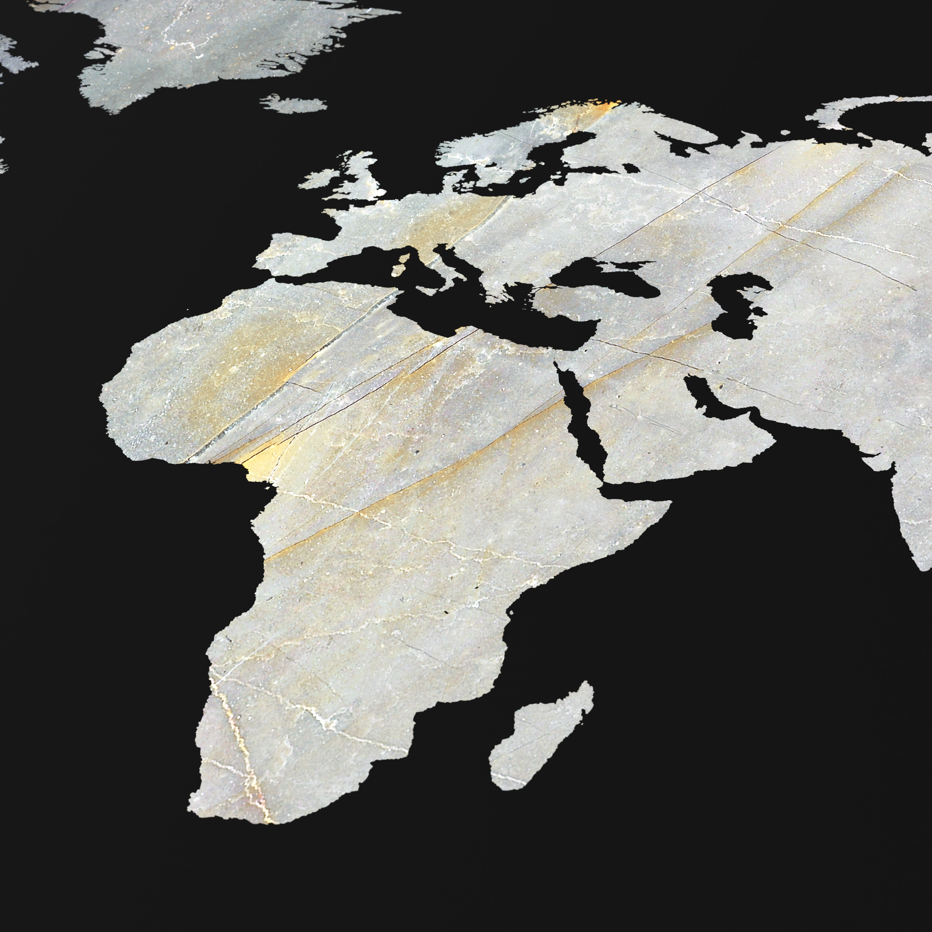 Eine Weltkarte aus Stein zeigt Europa, Afrika und Nahost vor schwarzem Hintergrund.