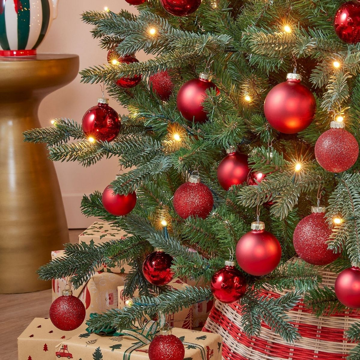 A Christmas tree decorated with red ornaments and lights, with gifts underneath.