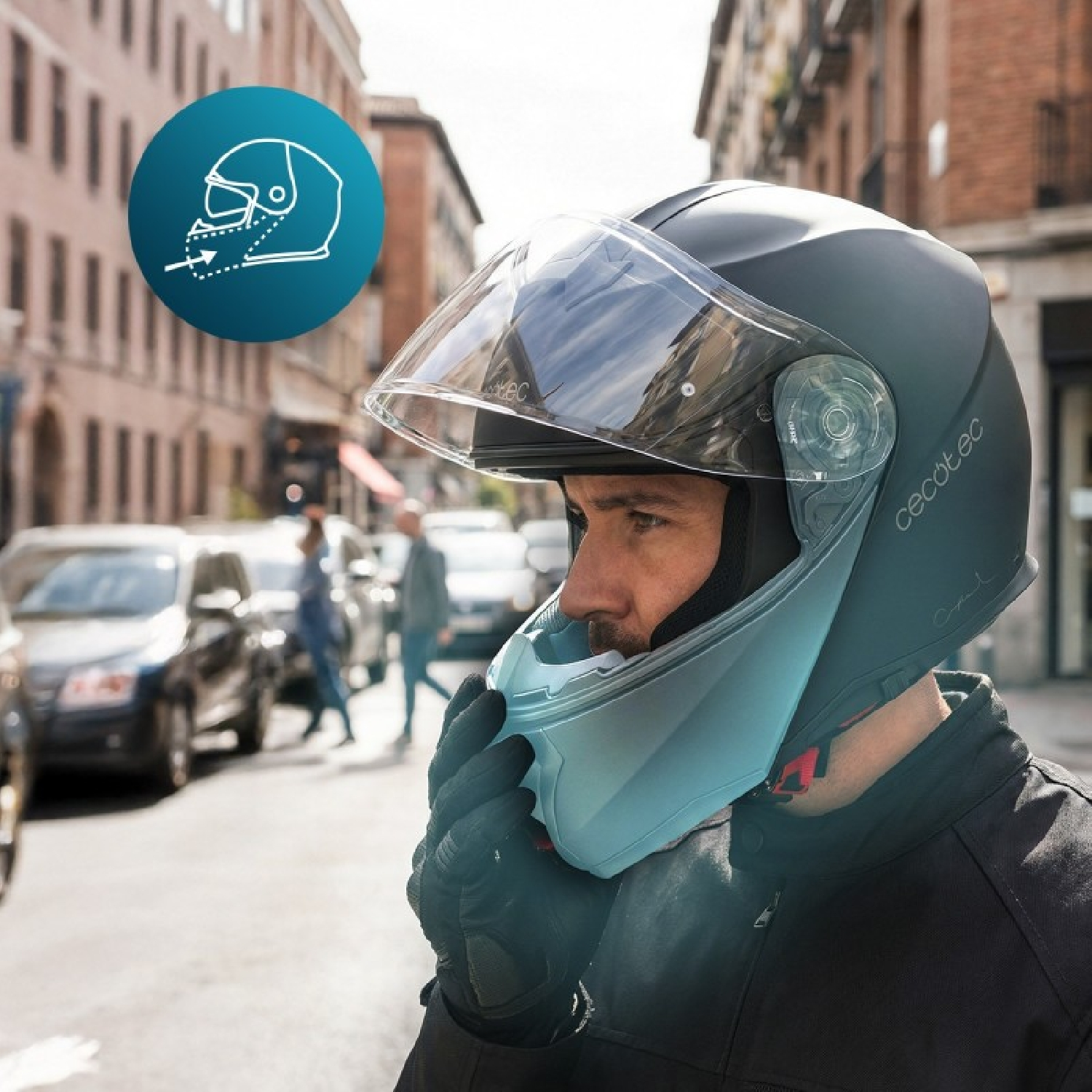 Un motociclista en una ciudad se coloca un casco negro con visera transparente y mentonera.
