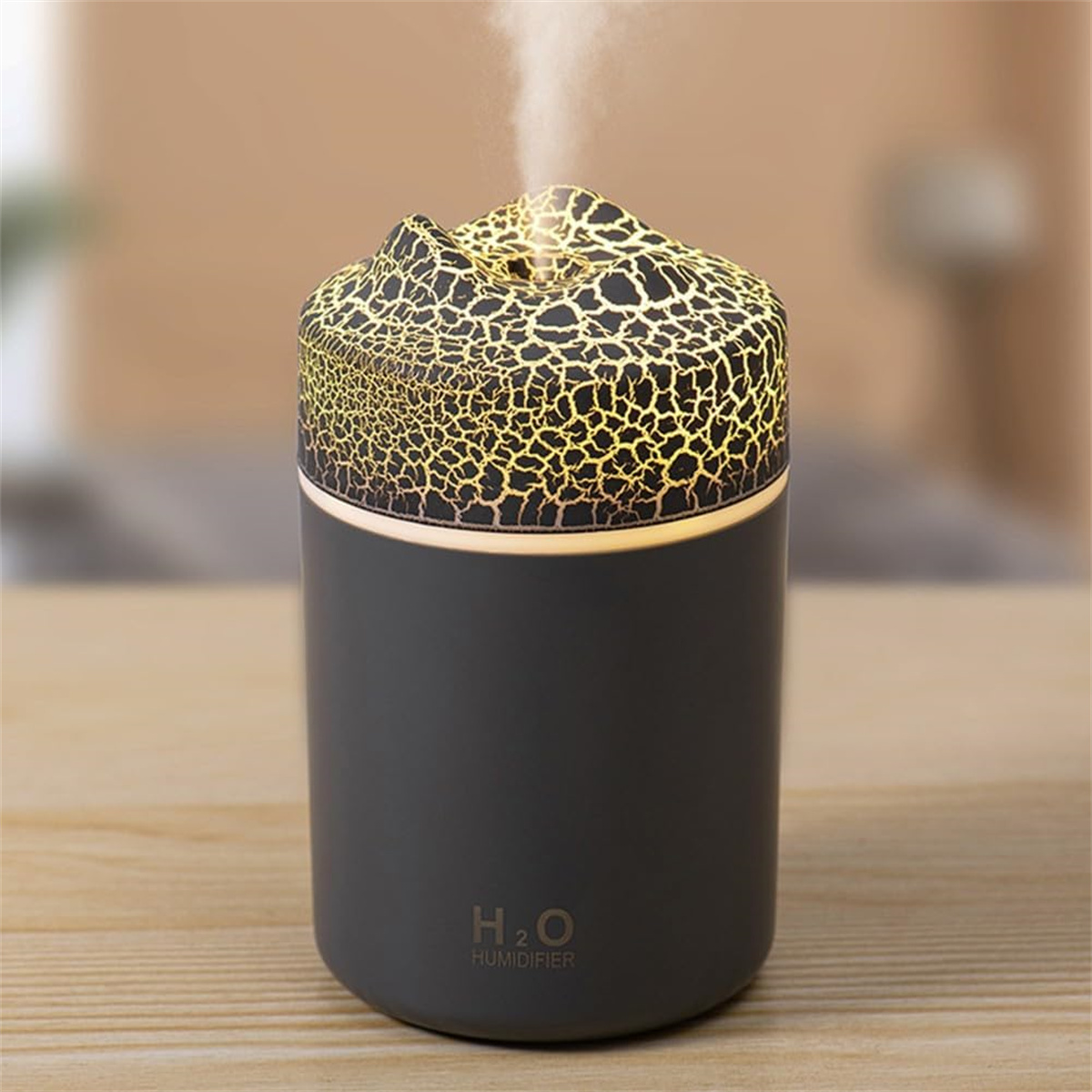 Ein schwarzer H2O Luftbefeuchter mit beleuchtetem, rissigem Muster oben stößt feinen Nebel aus.