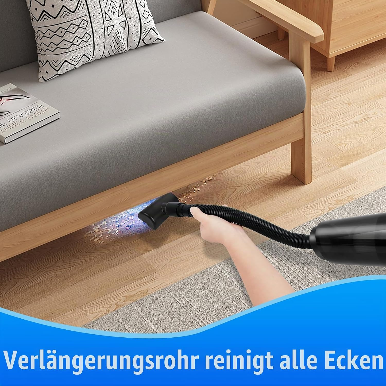 Ein Handstaubsauger mit Verlängerungsrohr reinigt den Holzboden unter einem Sofa.