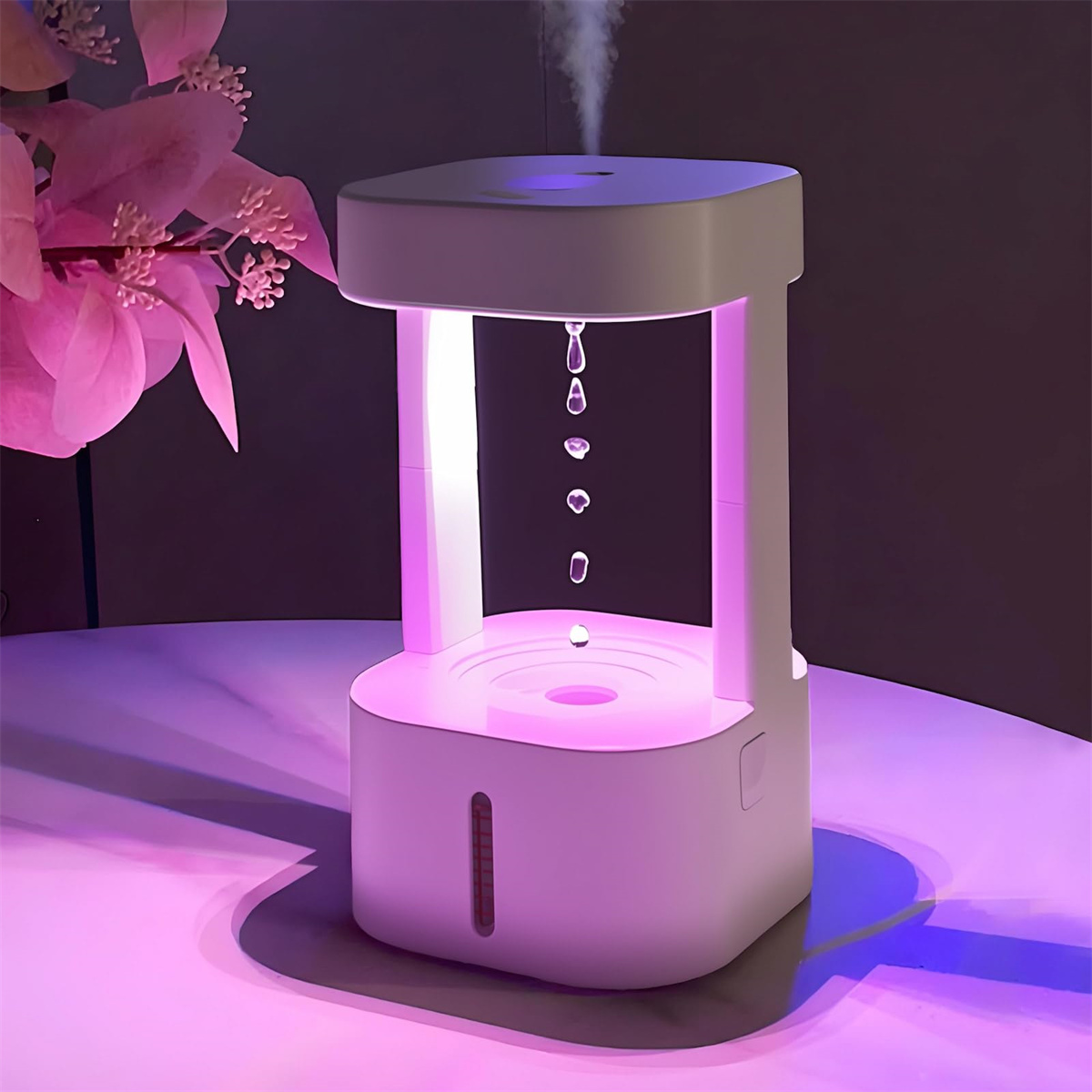 Ein weißer Anti-Schwerkraft-Wassertropfen-Luftbefeuchter auf einem Tisch, der rosa leuchtet.