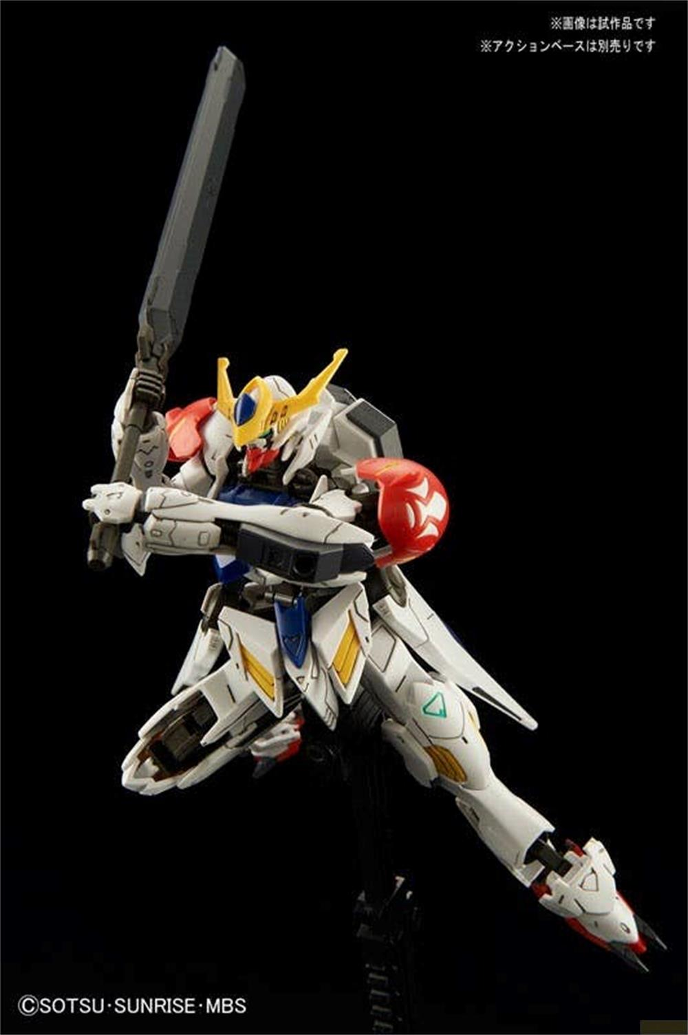Ein weiß-roter Gundam-Roboter auf einem Ständer, der ein großes Schwert in dynamischer Pose gegen schwarzem Hintergrund hält.