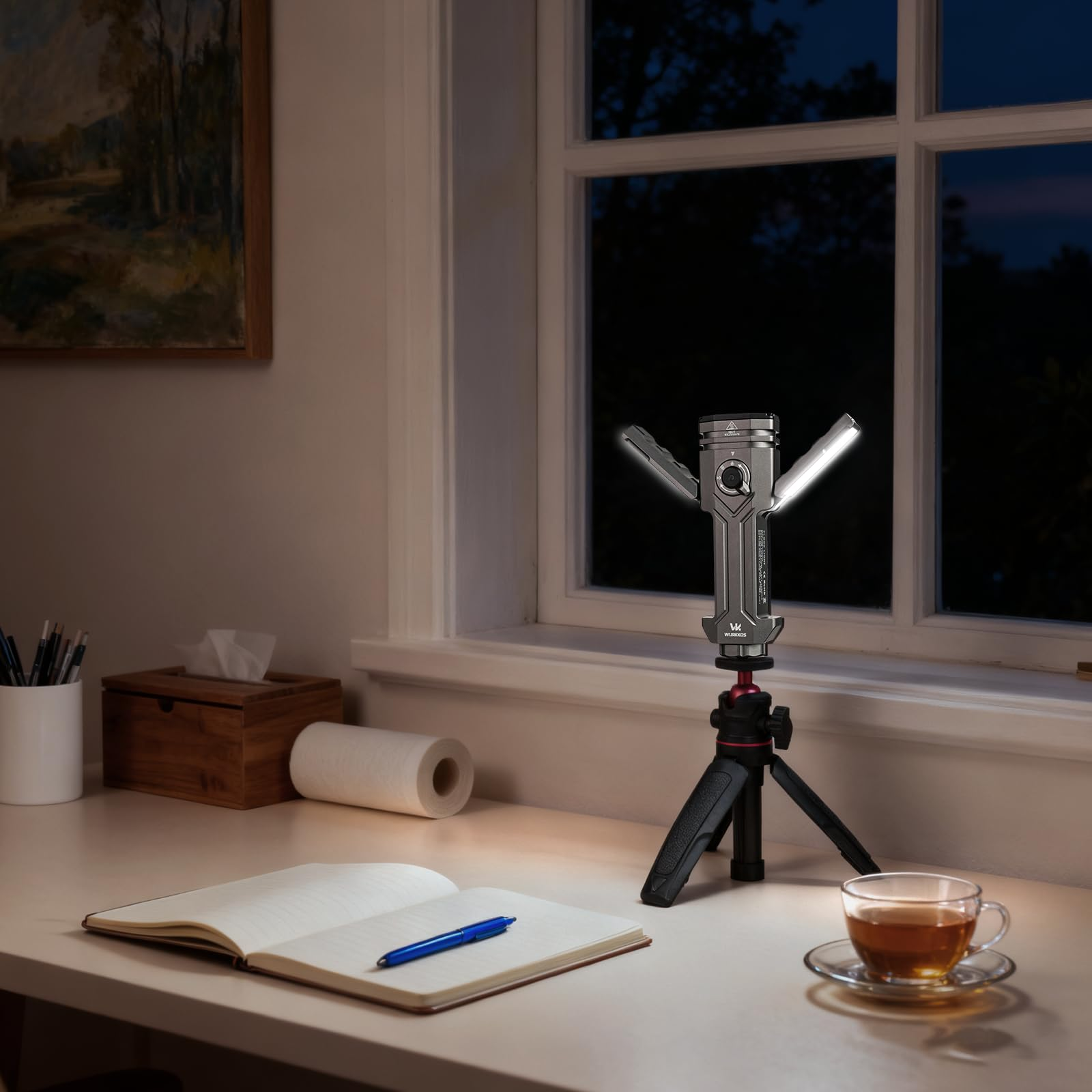 Eine graue Taschenlampe auf ein kleines Stativ montiert, beleuchtet einen Schreibtisch nachts.