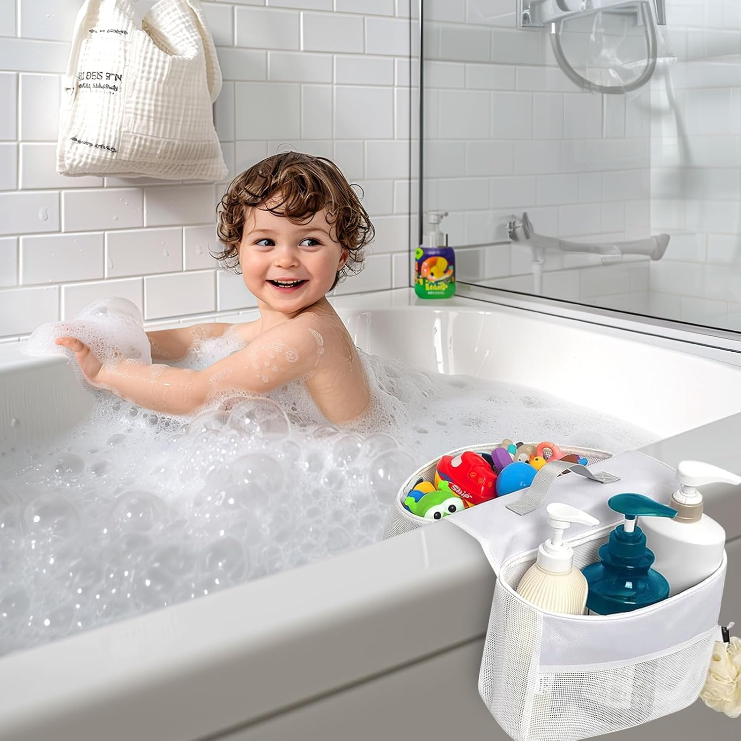 Ein lächelndes Kleinkind in einer mit Schaum gefüllten Badewanne neben einem Hängeorganizer mit Spielzeug und Seife.