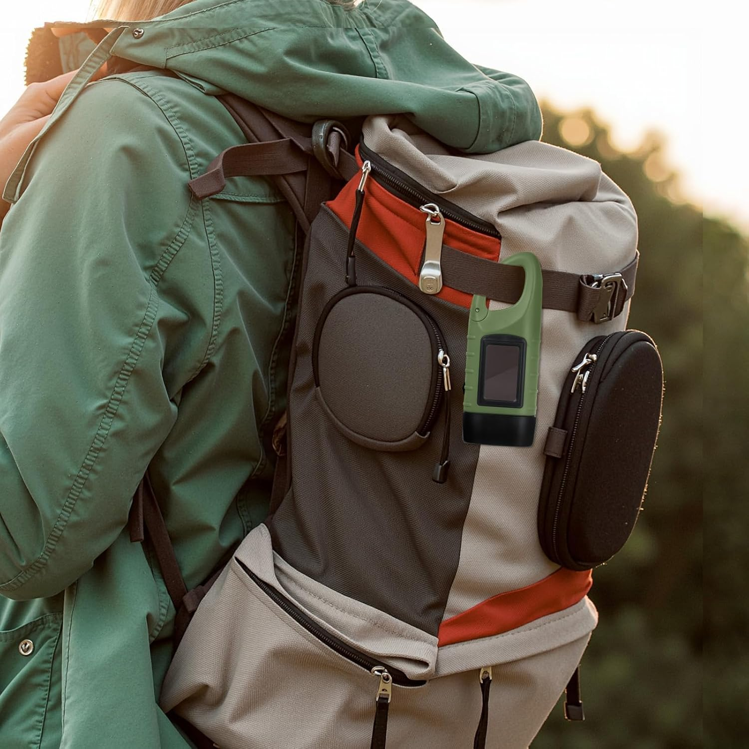 Eine Person trägt eine grüne Jacke und einen grau-orangen Rucksack im Freien.