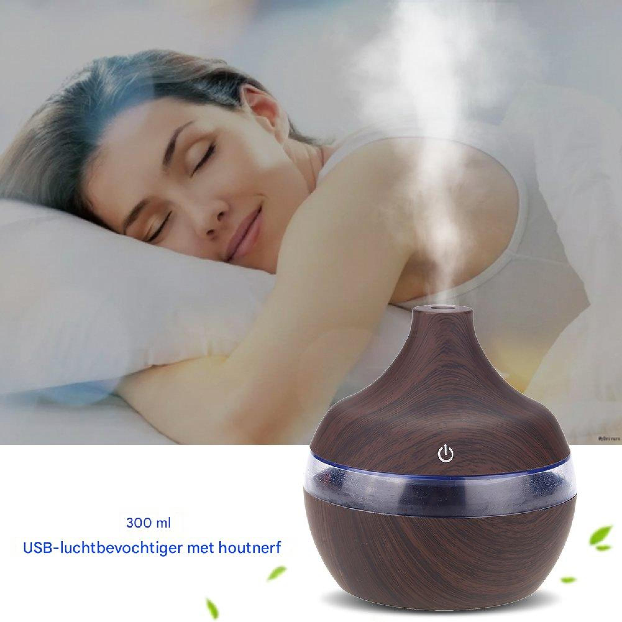 Ein USB-Luftbefeuchter mit Holzmaserung gibt Nebel ab, während eine Frau im Hintergrund friedlich schläft.