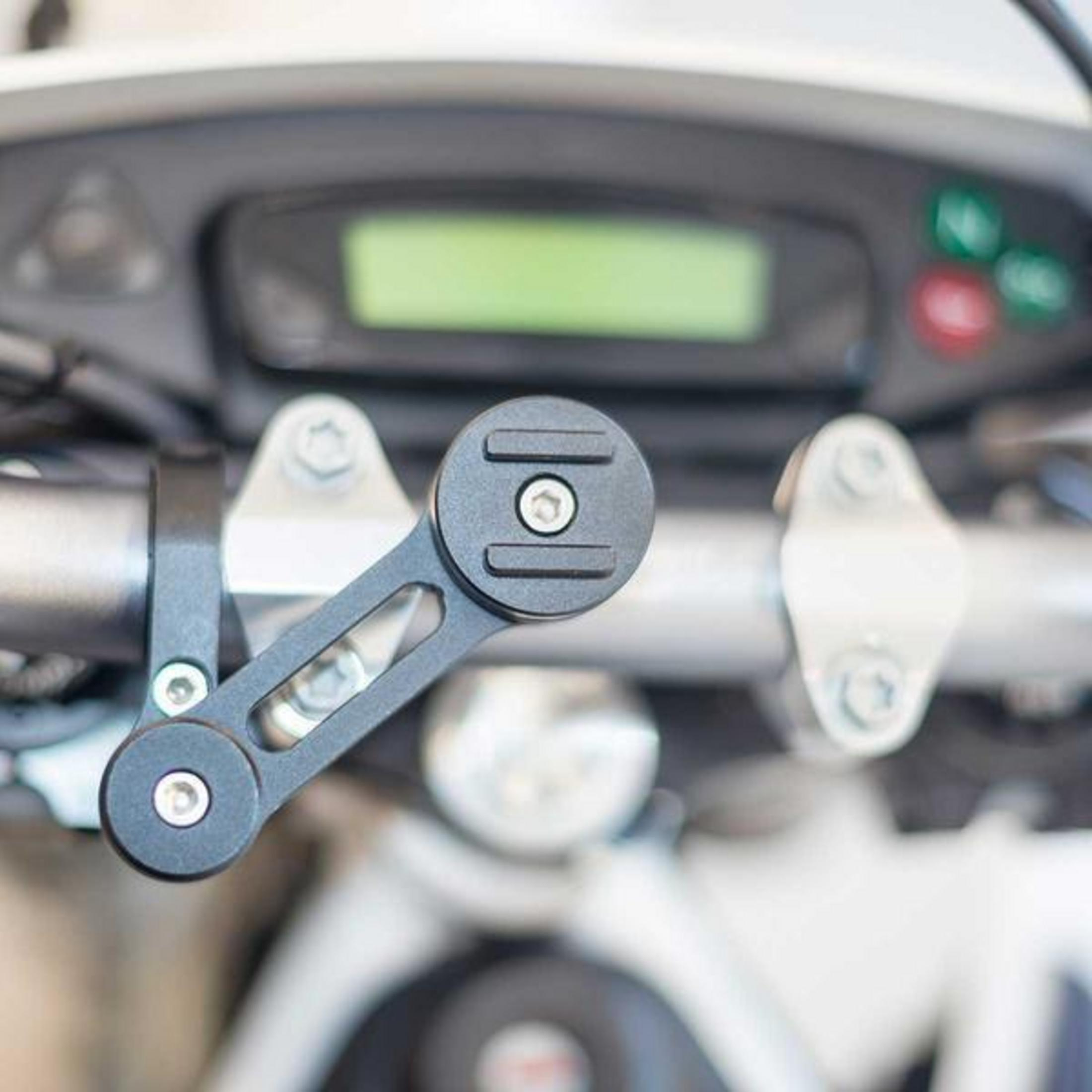 Eine schwarze Metallhalterung ist am silbernen Motorradlenker befestigt, im Hintergrund ist die Instrumententafel sichtbar.