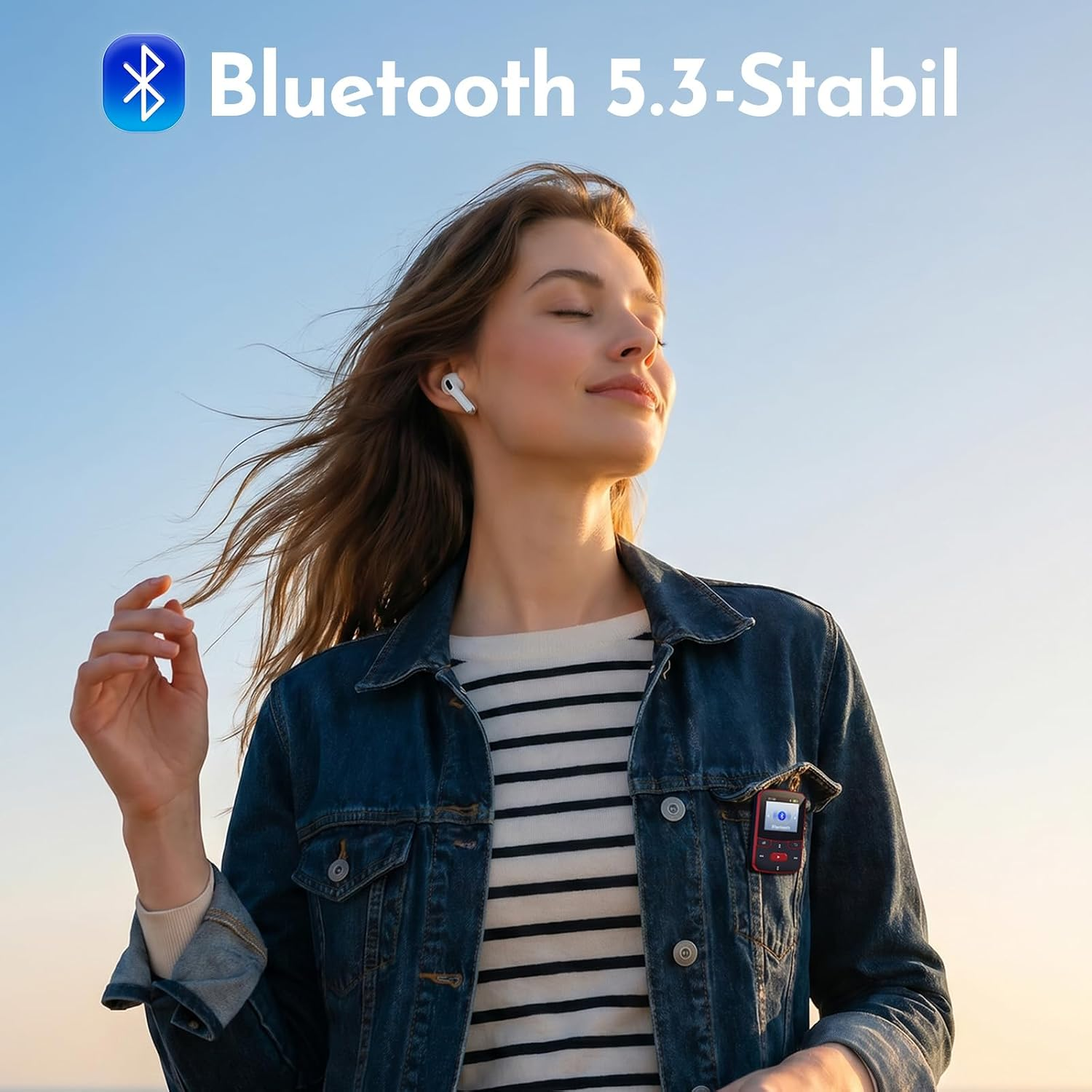 Eine junge Frau mit geschlossenen Augen trägt eine Jeansjacke, weiße Ohrstöpsel und einen MP3-Player vor blauem Himmel.