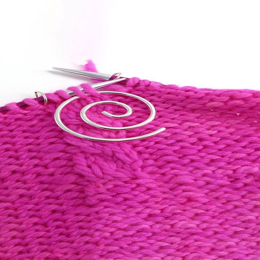 Helles pinkfarbenes Strickgewebe mit einer silbernen Spiral-Zopfnadel oben vor weißem Hintergrund.