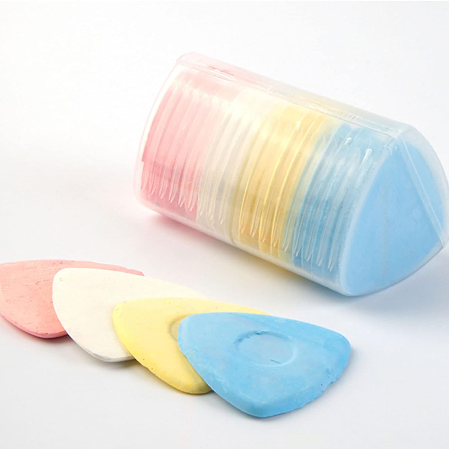 Ein durchsichtiges Plastiketui enthält bunte, dreieckige Schneiderkreide in Rosa, Weiß, Gelb und Blau auf Weiß.