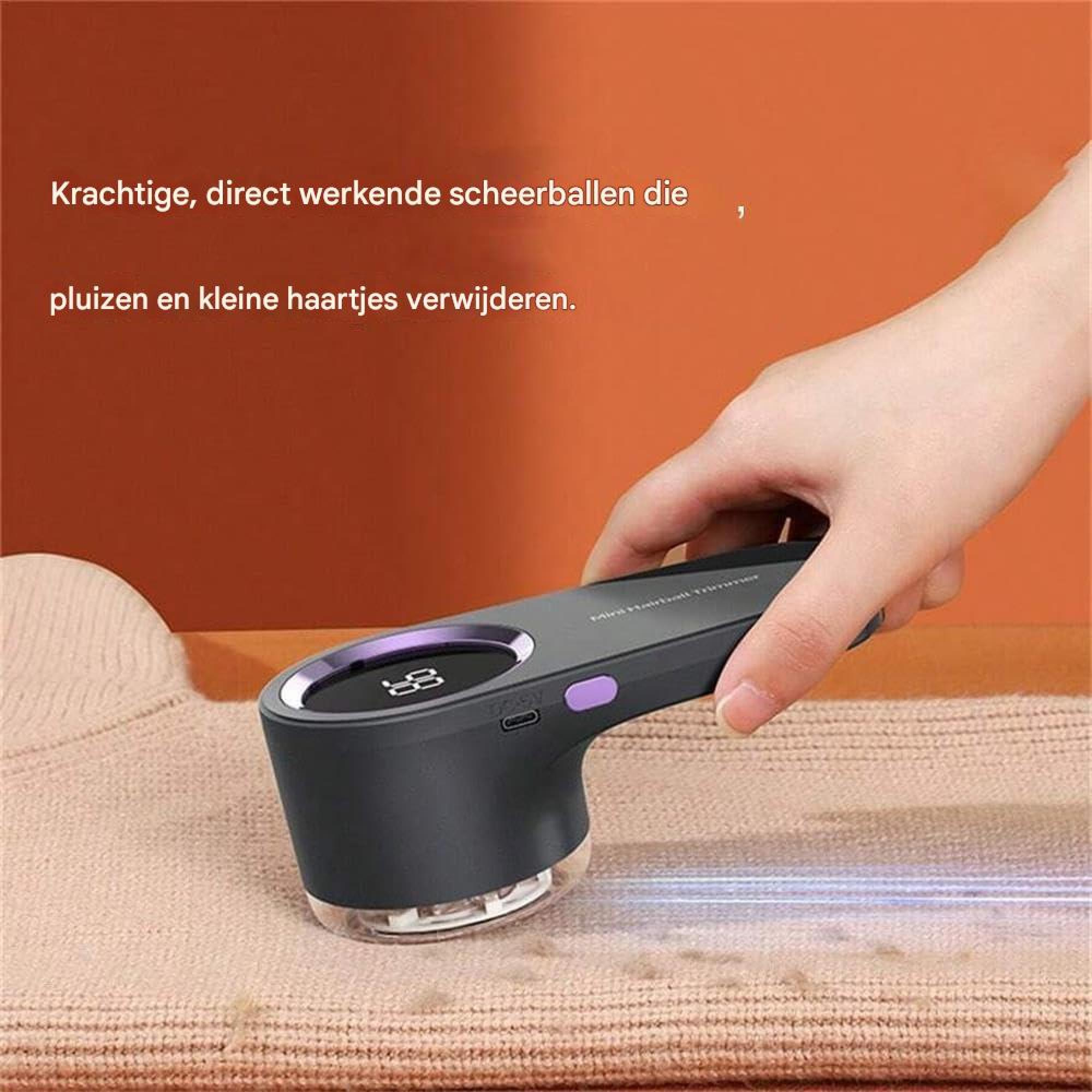 Eine Hand hält einen dunkelgrauen Fusselrasierer und führt ihn über einen beige Strickstoff vor orangefarbenem Hintergrund.