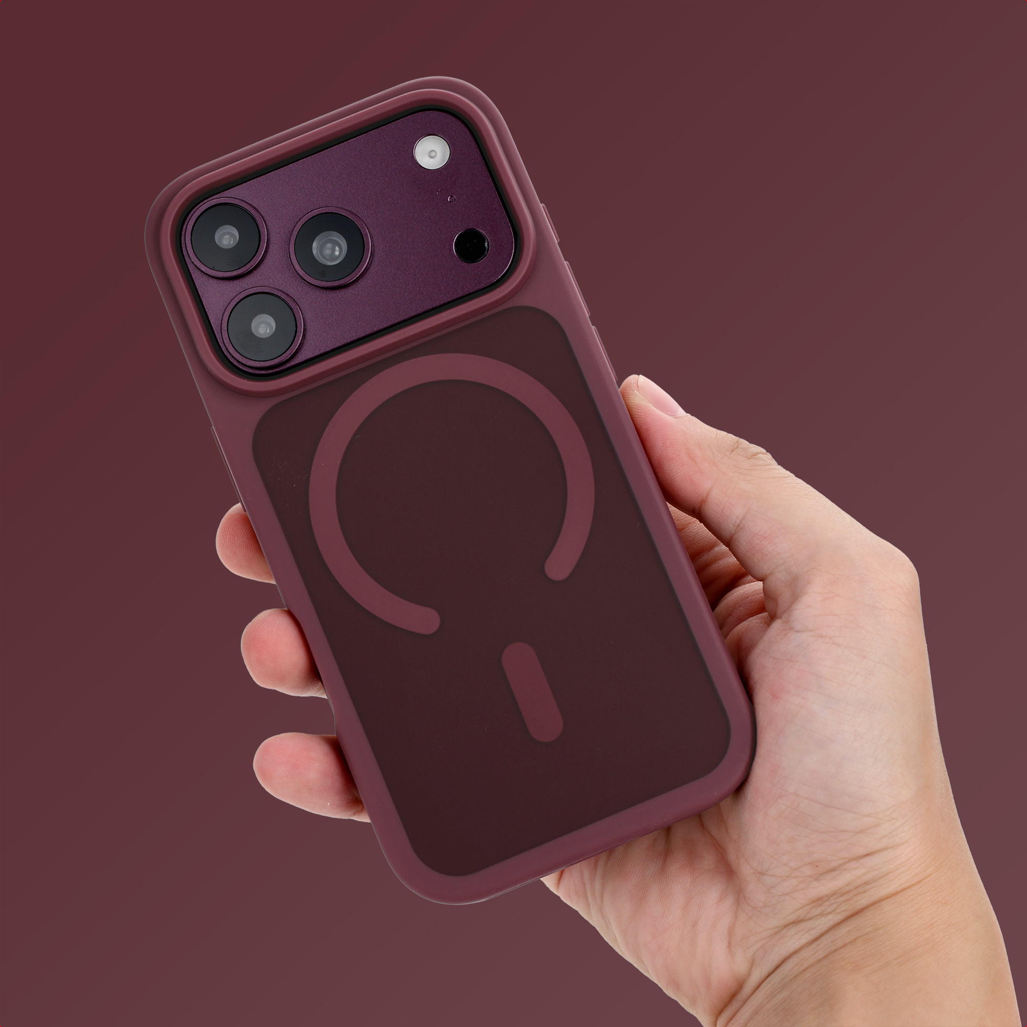 Eine Hand hält ein violettes iPhone mit MagSafe-Hülle vor dunklem Hintergrund.