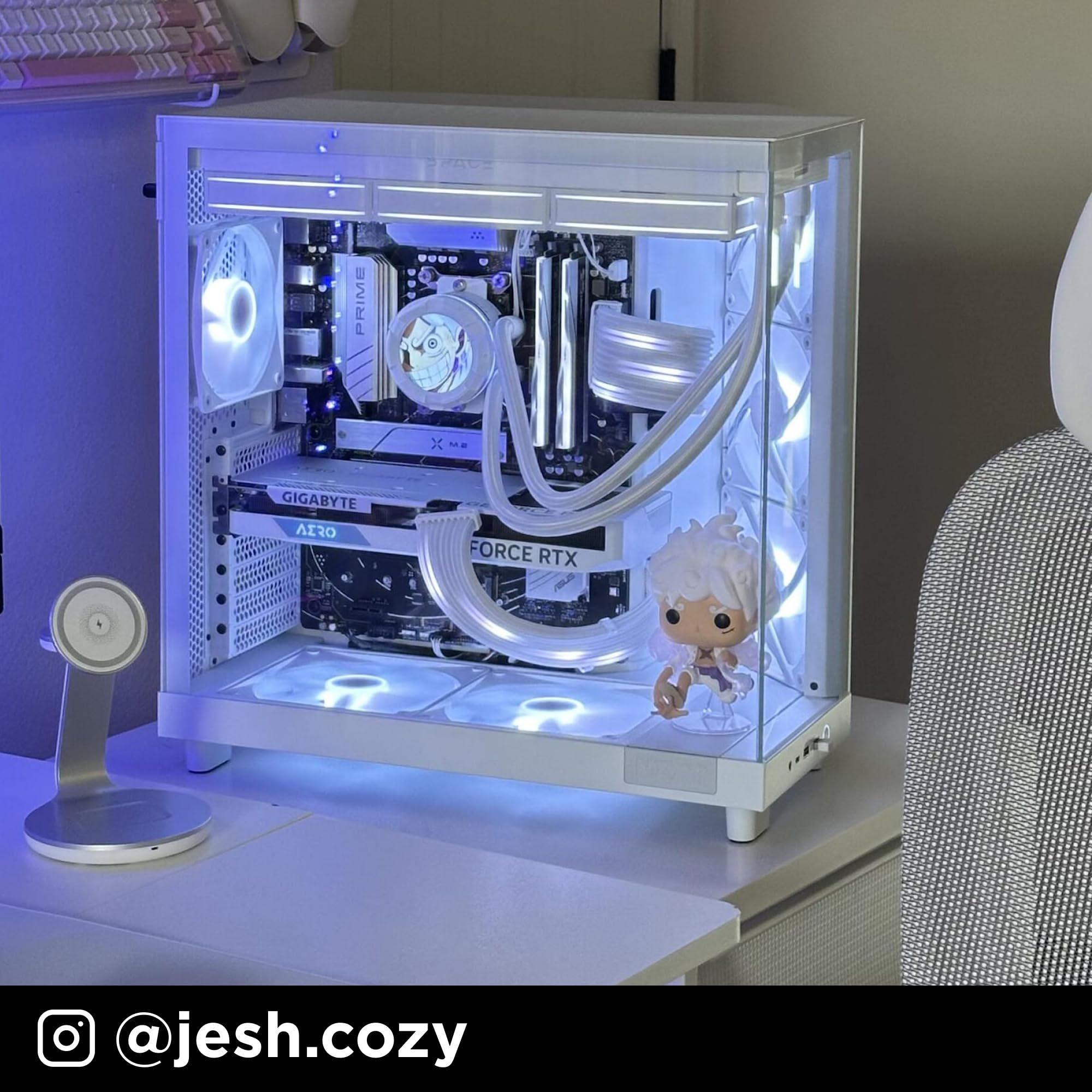 Un PC de jeu blanc avec éclairage interne bleu et blanc, refroidissement liquide et une petite figurine animée.