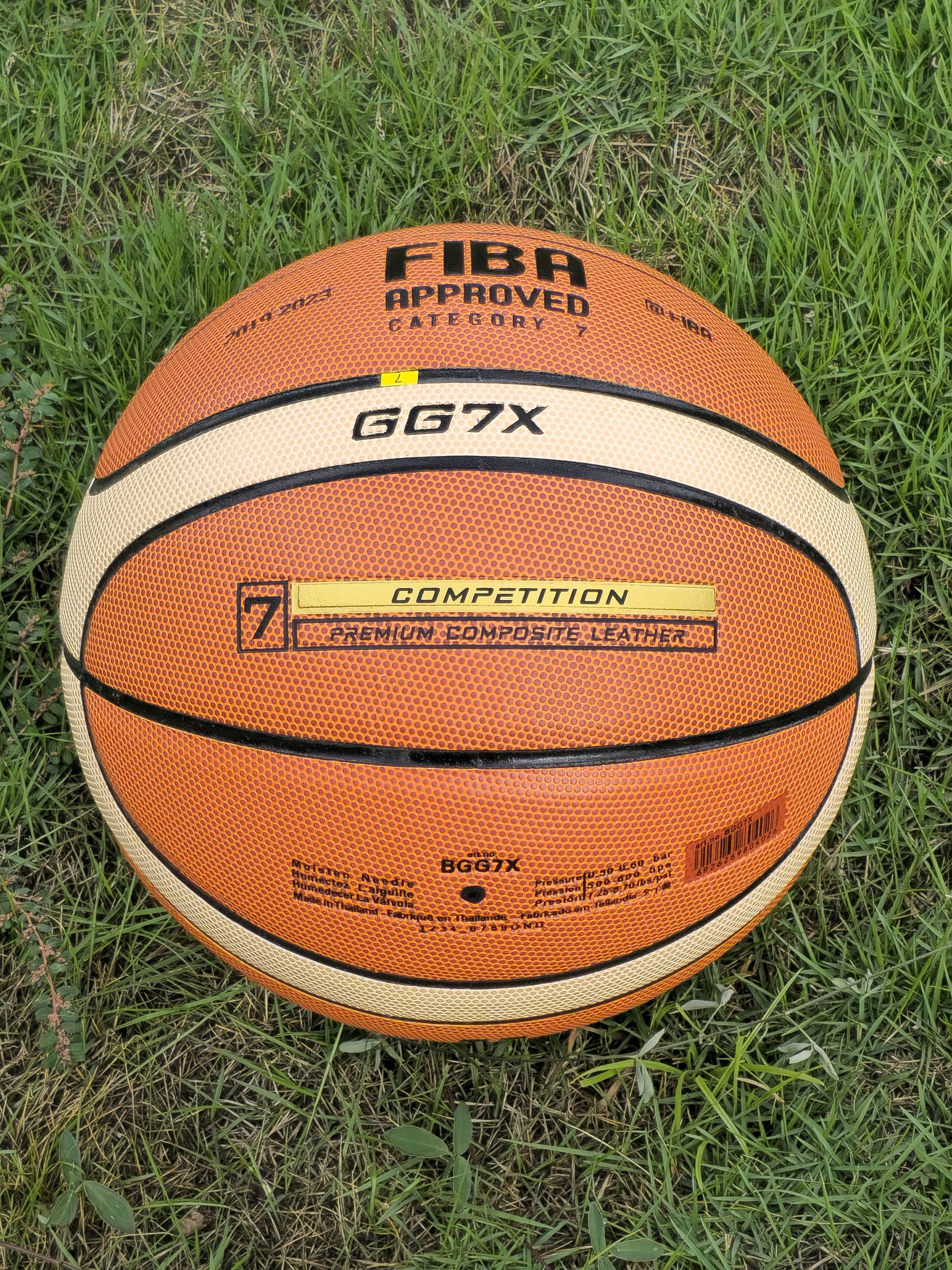Ein orangefarbener Basketball mit schwarzen Linien und FIBA-Logo liegt im grünen Gras.