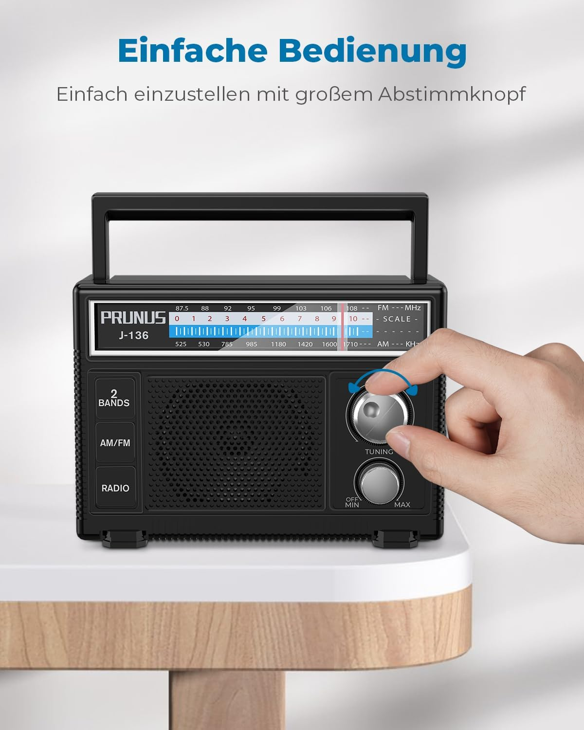 Eine Hand dreht den grossen Abstimmknopf eines schwarzen Prunus J-136 Radios.