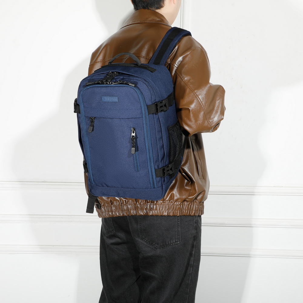 Una persona con chaqueta de cuero marrón y mochila azul se encuentra ante una pared blanca.