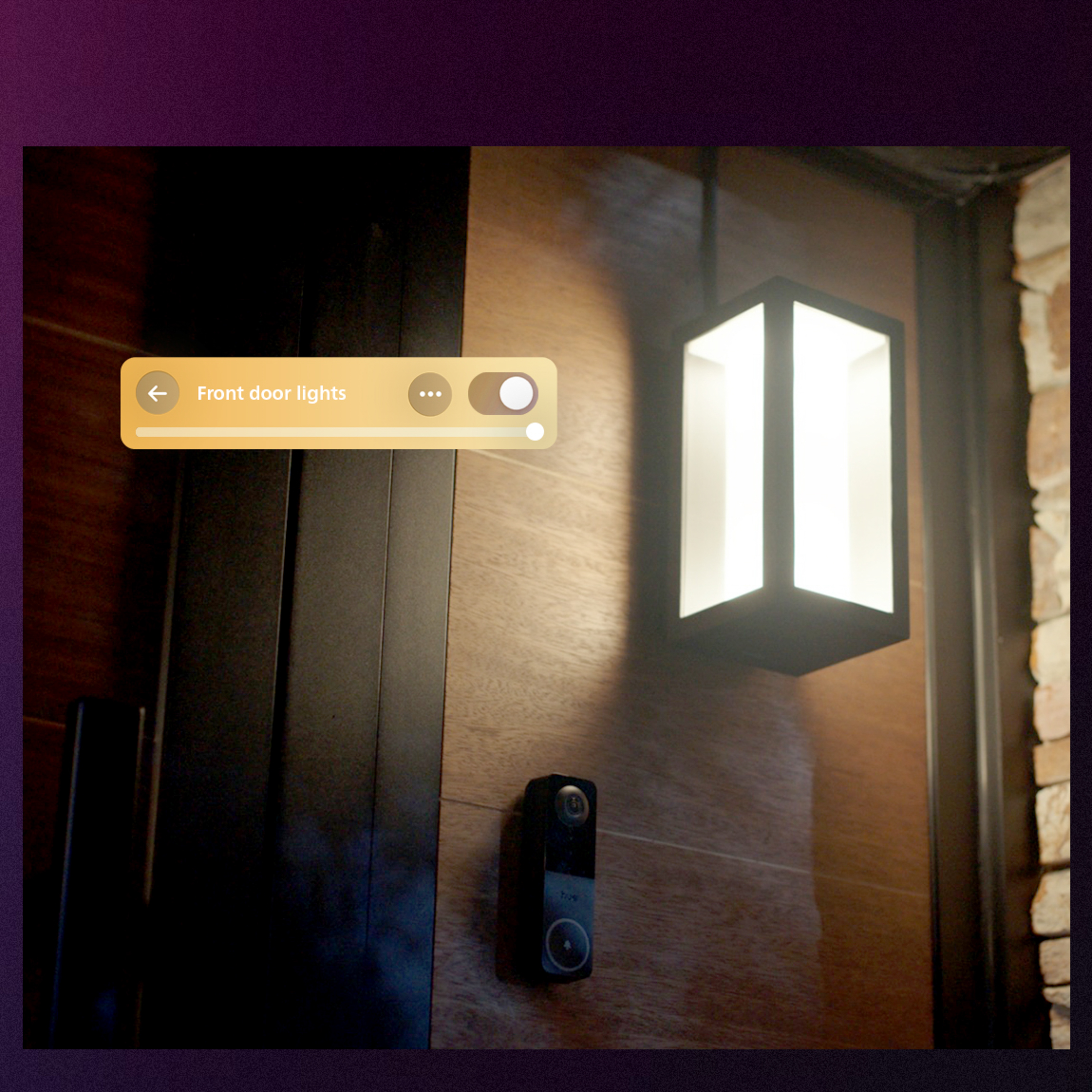 Beleuchtete moderne Außenlampe und smarte Türklingel an einer holzverkleideten Wand.