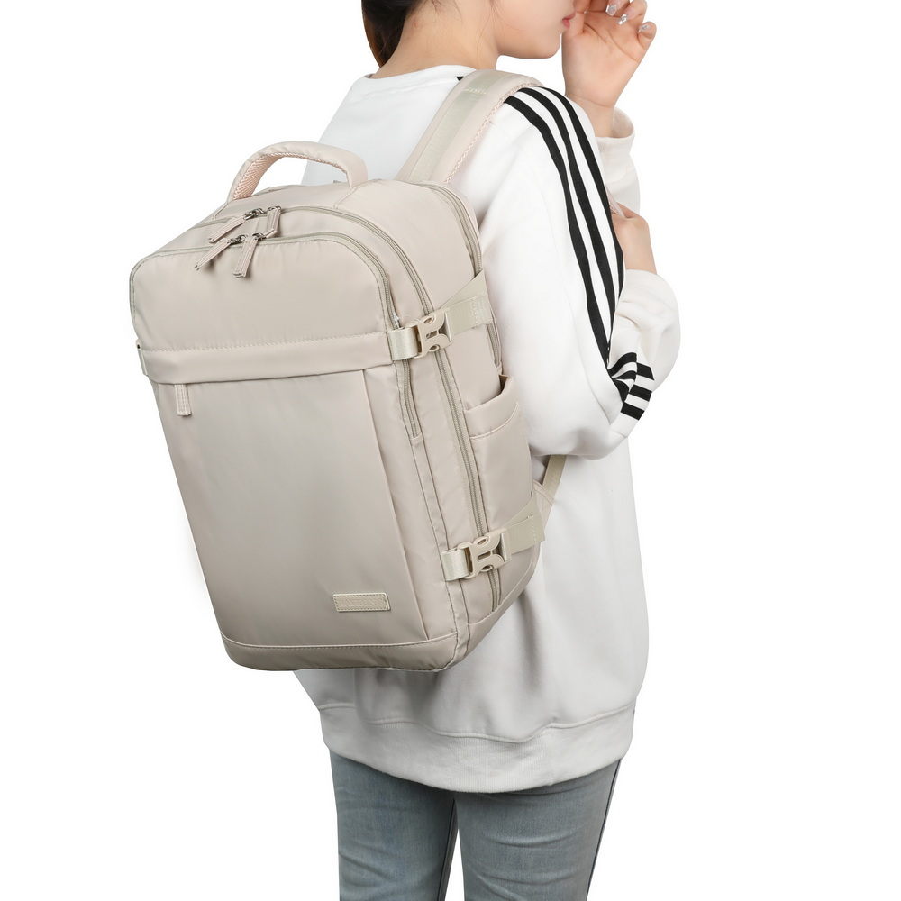 Una mujer lleva una mochila grande de color beige claro en la espalda sobre fondo blanco.