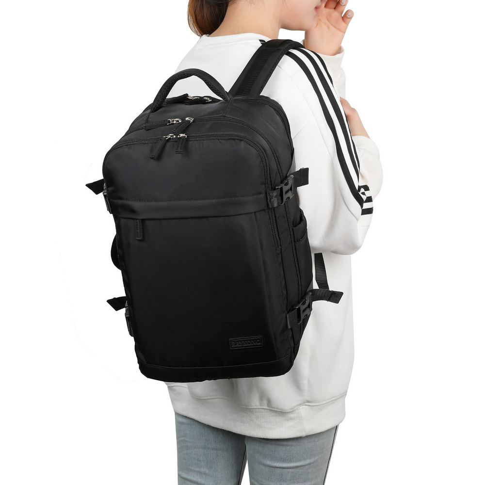 Una persona con una mochila negra grande, suéter blanco a rayas y vaqueros claros sobre un fondo blanco.