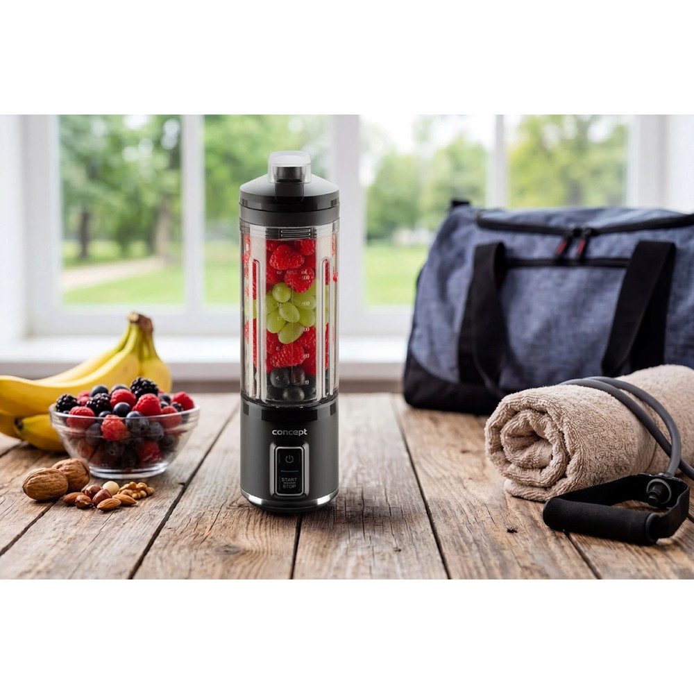 Przenośny blender z jagodami i winogronami na drewnianym stole, z owocami, ręcznikiem i torbą sportową.