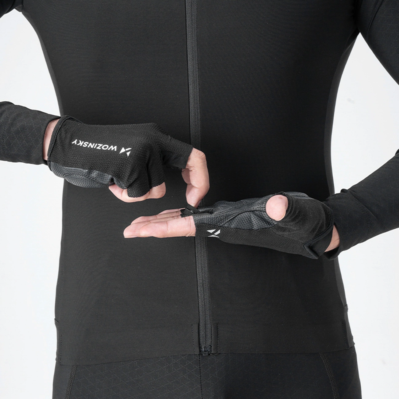 Persona in abbigliamento da ciclismo nero mostra guanti da ciclismo Wozinsky d mezzo dito.