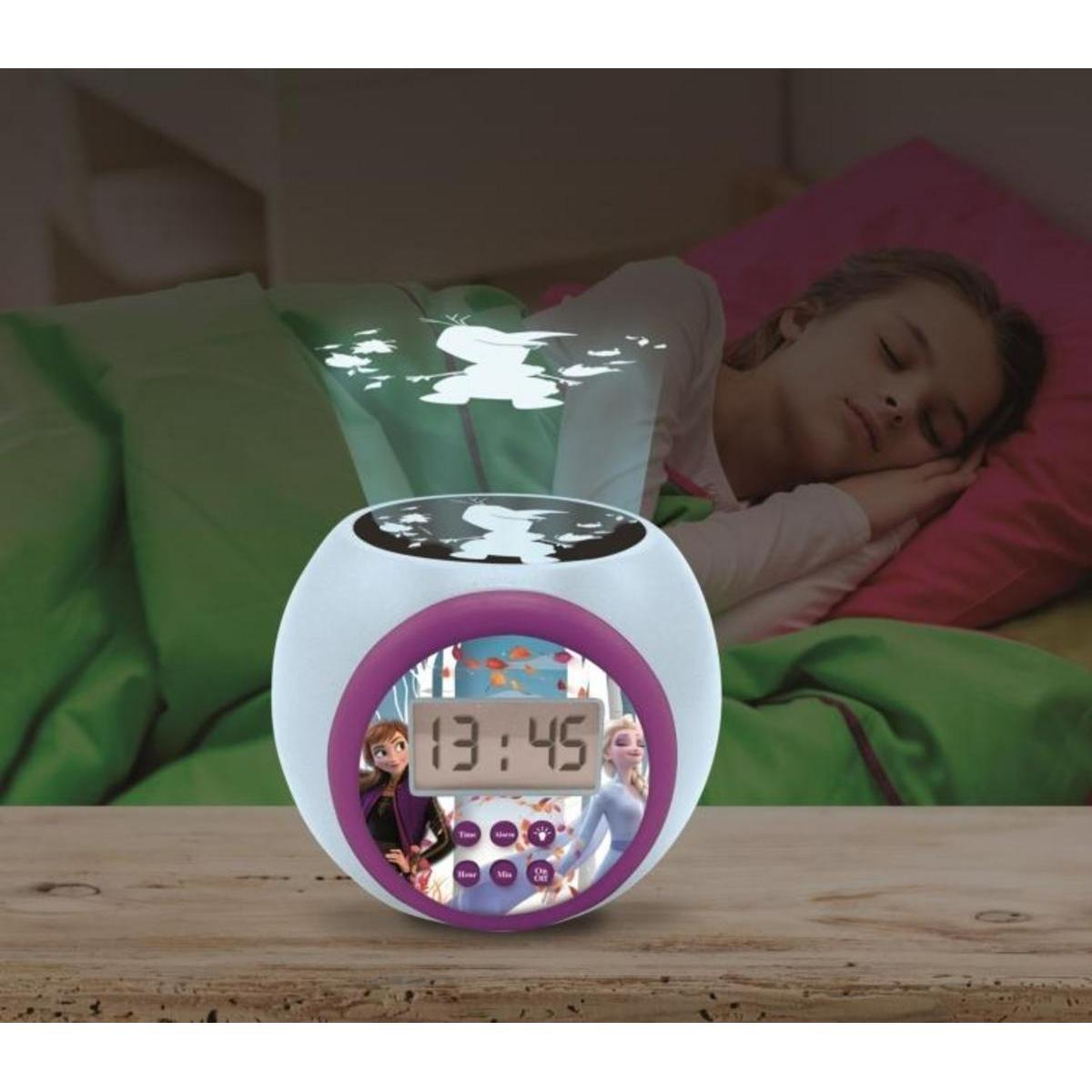 Ein Elsa- und Anna-Wecker auf einem Holz Tisch projiziert ein Bild an die Wand, während ein Mädchen im Bett schläft.