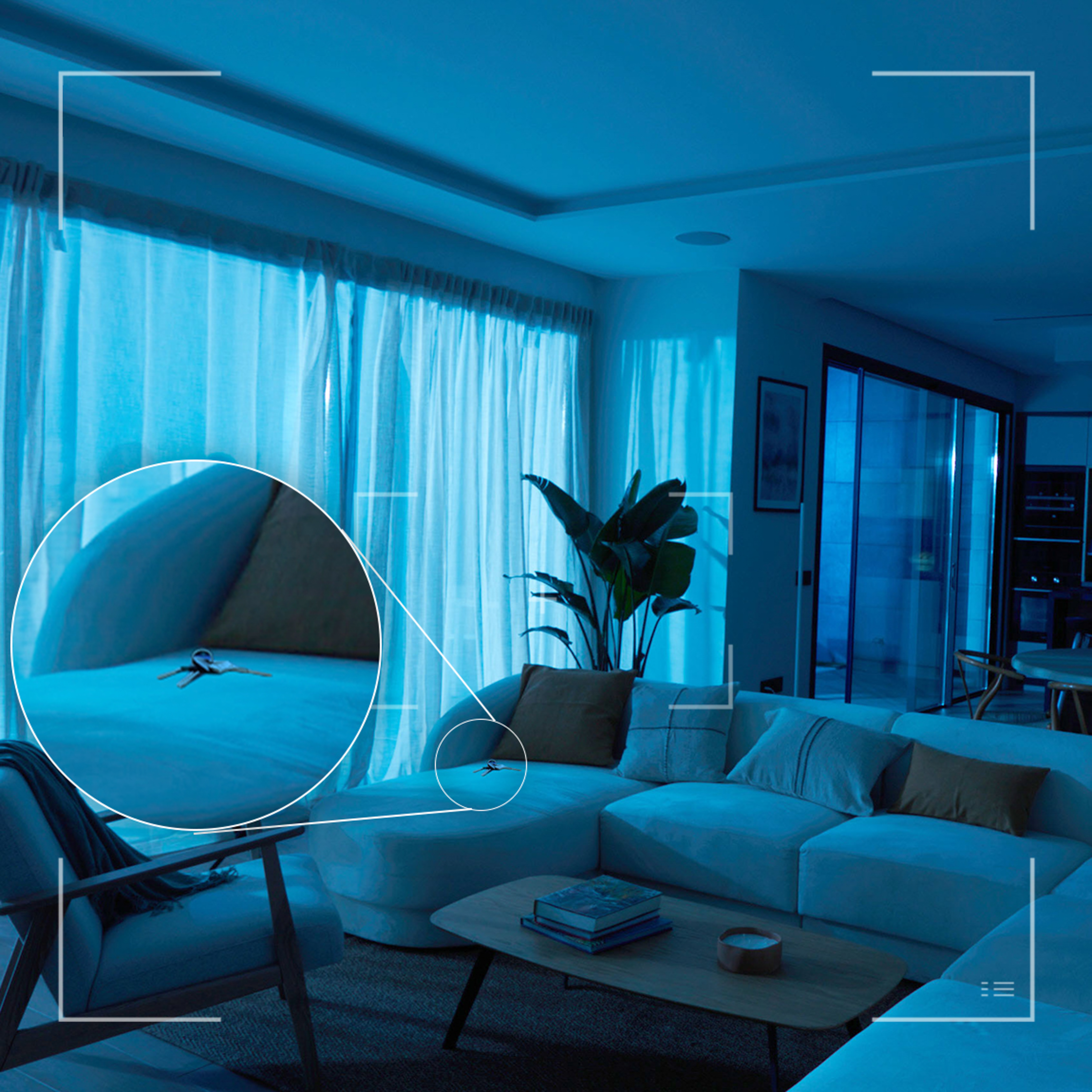 Blaulicht-Wohnzimmer mit Sofa, Couchtisch und einer vergrößerten Ansicht von Schlüsseln auf dem Sofa.