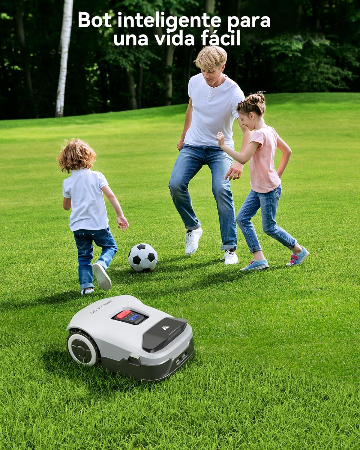 Un padre y dos niños juegan al fútbol en el jardín mientras un robot cortacésped blanco está en el césped.