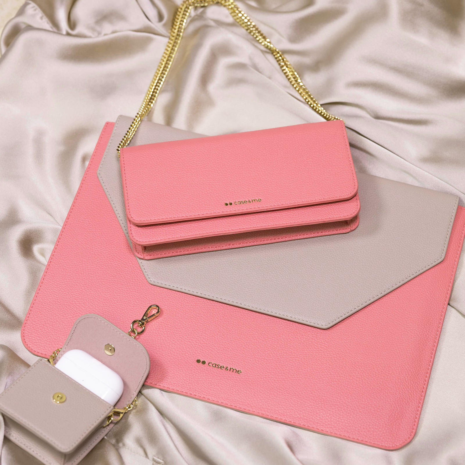 Funda rosa y beige, bolso rosa a juego y estuche para auriculares sobre tela sedosa.