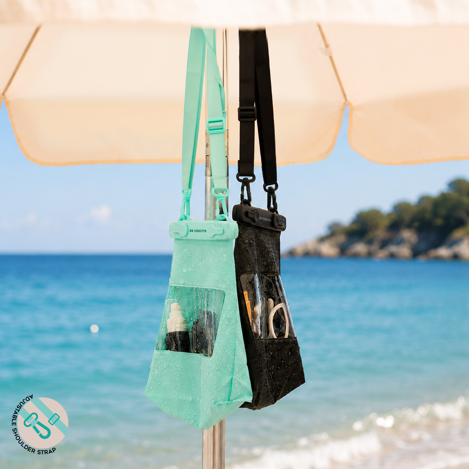 Dos bolsas impermeables, una verde menta y otra negra, cuelgan del poste de una sombrilla con el mar de fondo.