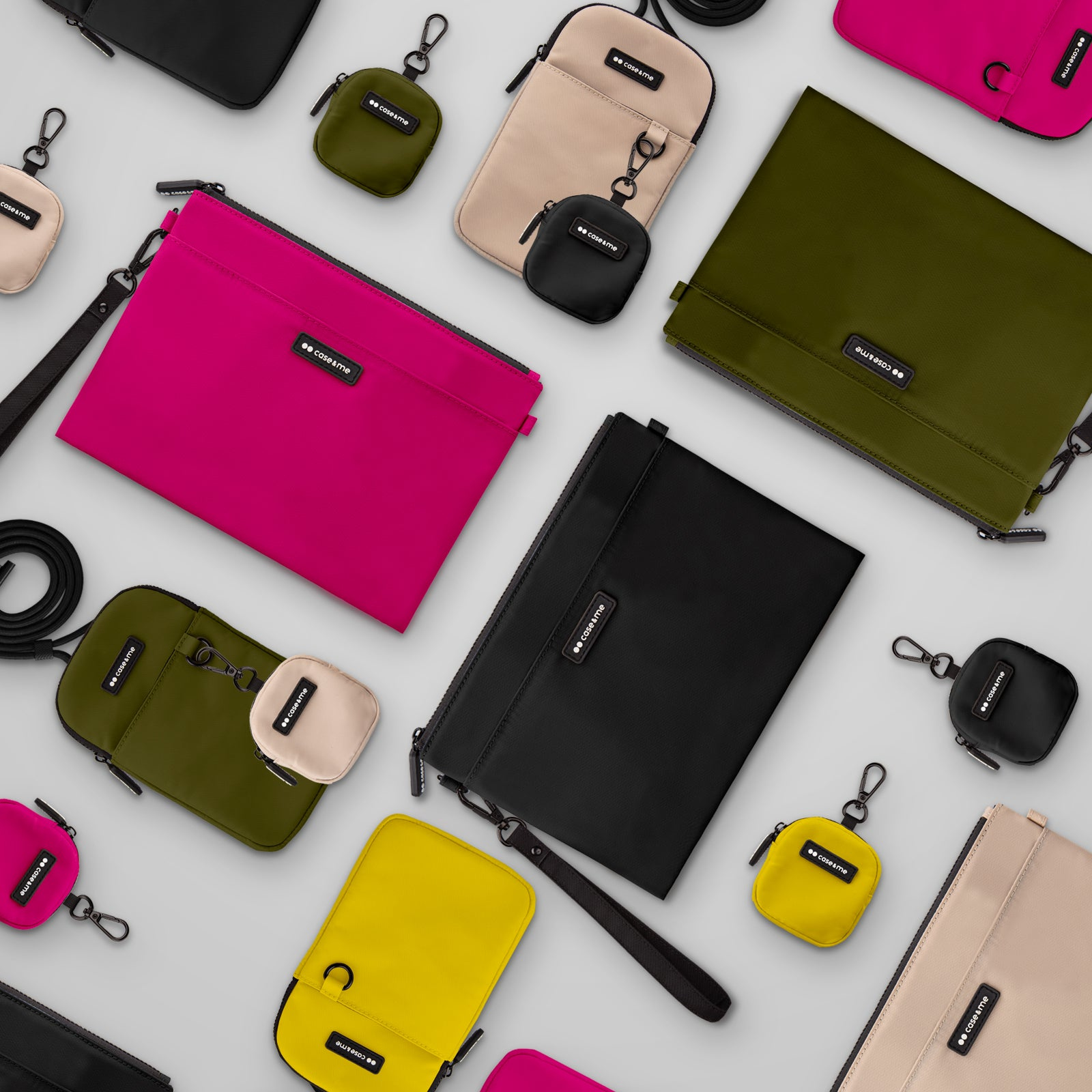 Una disposición de bolsos coloridos y estuches pequeños sobre un fondo gris claro.
