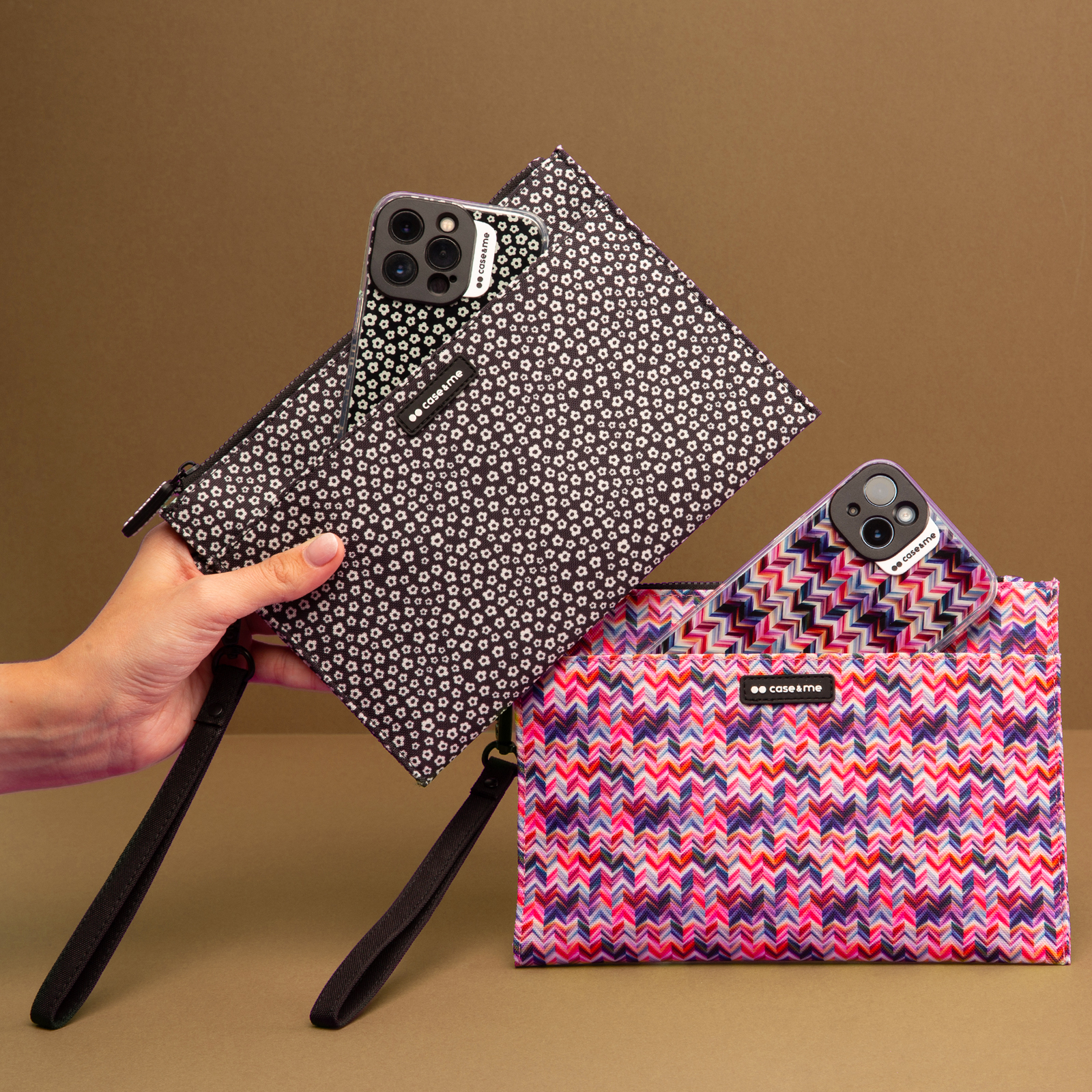 Una mano sostiene una bolsa floral en blanco y negro con un smartphone a juego, junto a una bolsa rosa con patrón.
