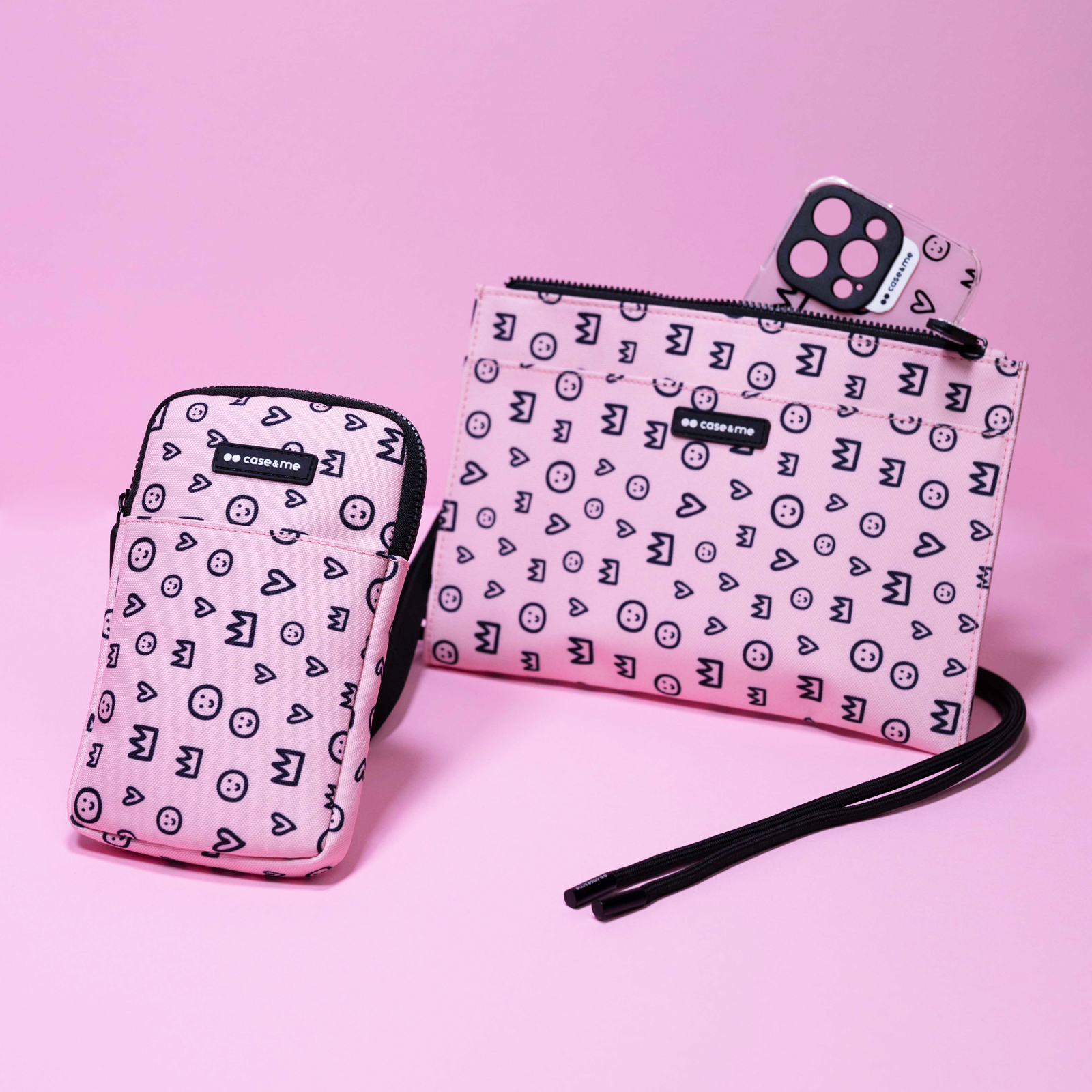 Dos bolsos rosas con un patrón negro de caras felices, corazones y coronas sobre un fondo rosa.