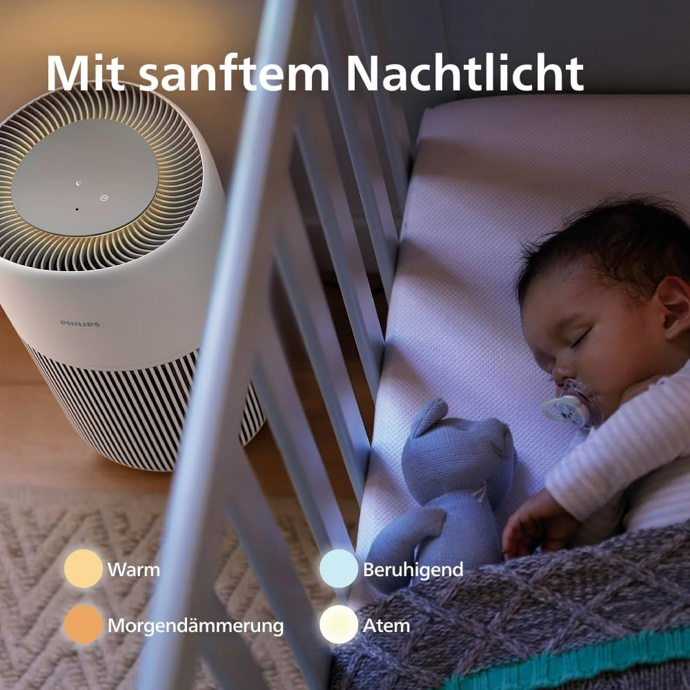 Ein Baby schläft in einem Bettchen neben einem Philips Luftreiniger mit Nachtlicht.