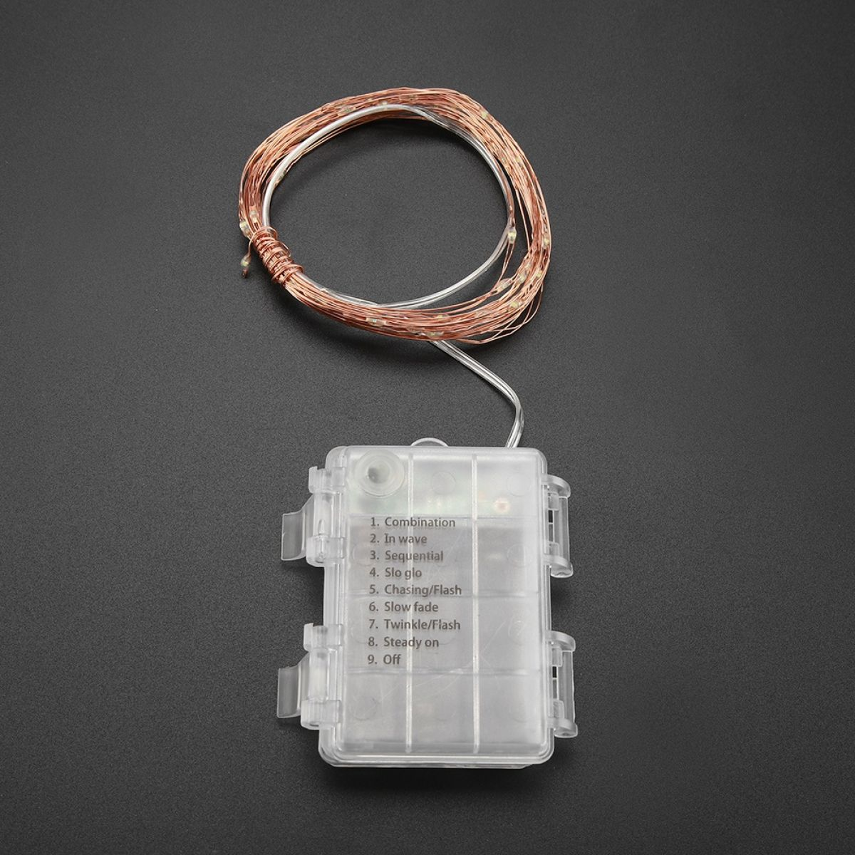 Eine Kupferdraht-Lichterkette mit durchsichtigem Batteriekasten und Modus-Text vor dunklem Hintergrund.