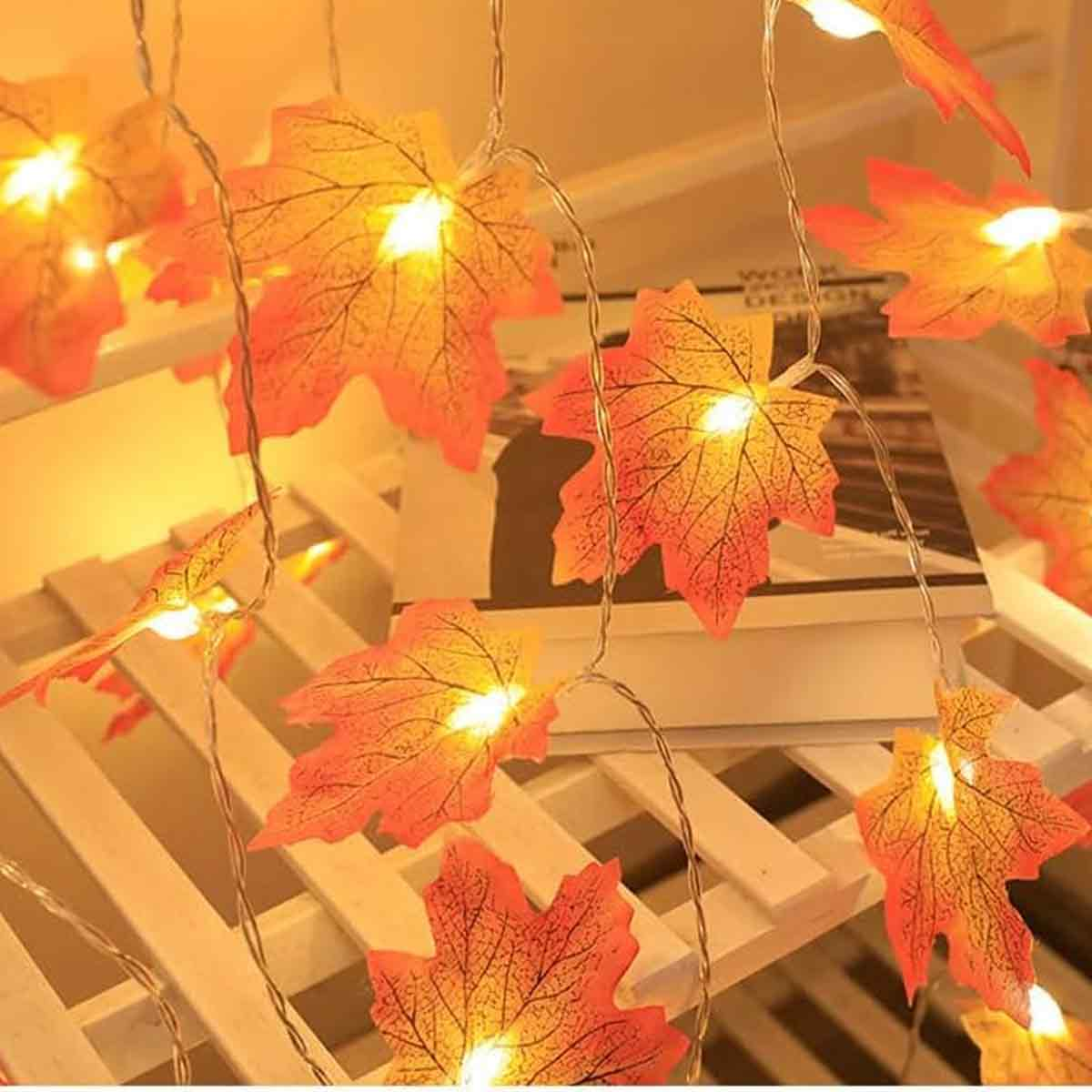 Lichterkette mit leuchtenden herbstlichen Ahornblättern in Orangetönen.