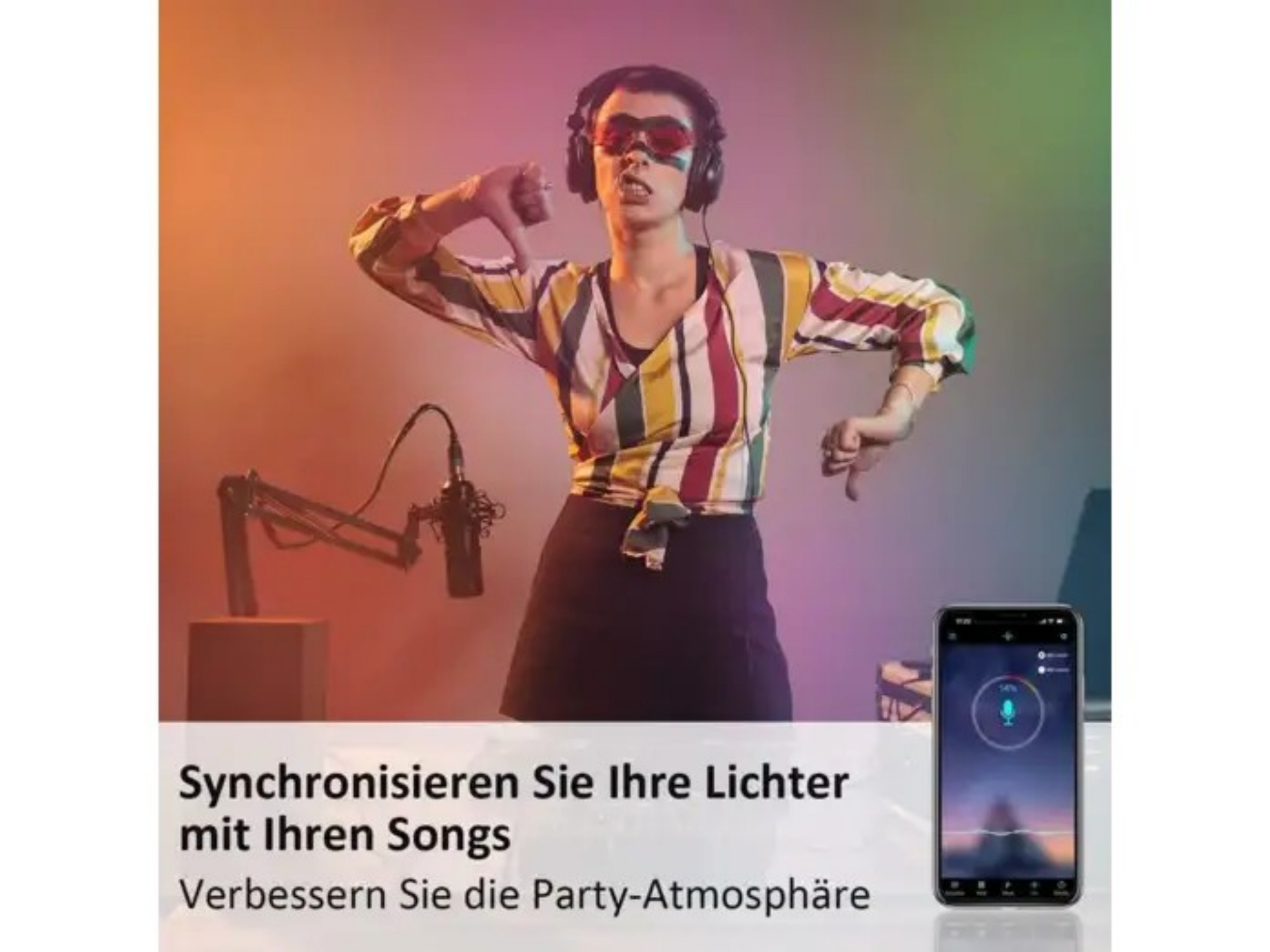Eine Person mit Kopfhörern tanzt im bunten Licht, Mikrofon und Handy mit Musik-App sind sichtbar.