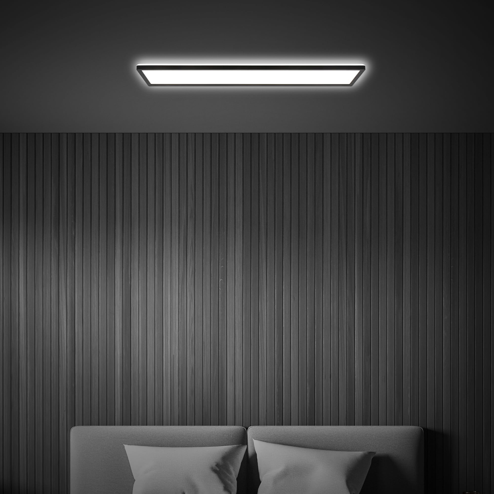 Una luminosa plafoniera brilla sopra una parete a listelli grigi e un letto con cuscini in una stanza buia.
