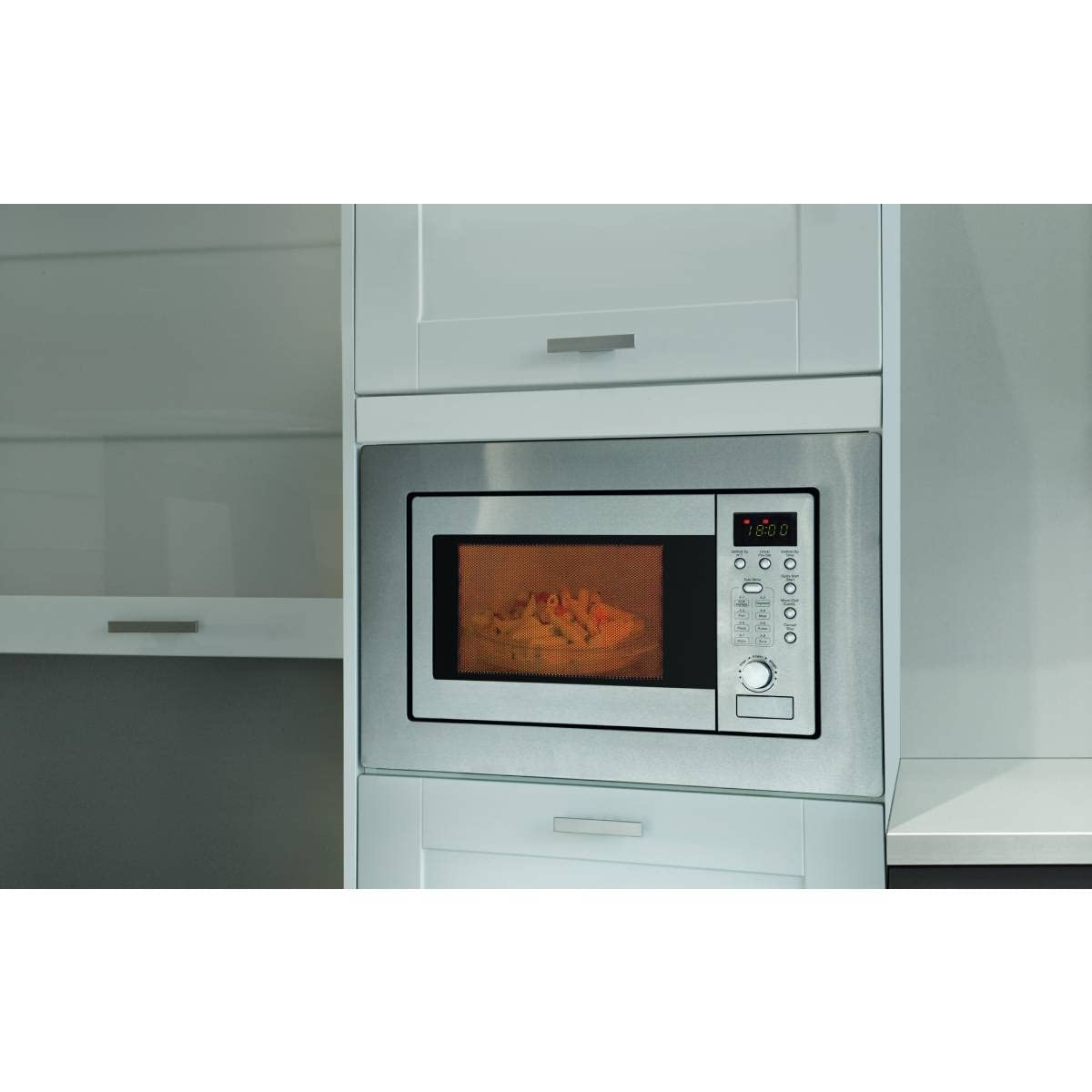 Un four à micro-ondes encastrable en acier inoxydable avec affichage numérique est intégré dans un meuble de cuisine blanc.